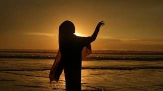 A woman standing on top of a beach next to the ocean