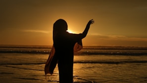 A woman standing on top of a beach next to the ocean