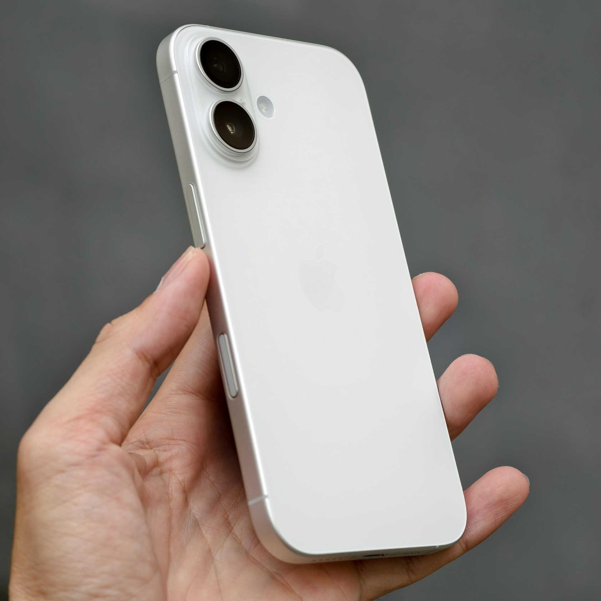 A person holding a white iPhone in their hand