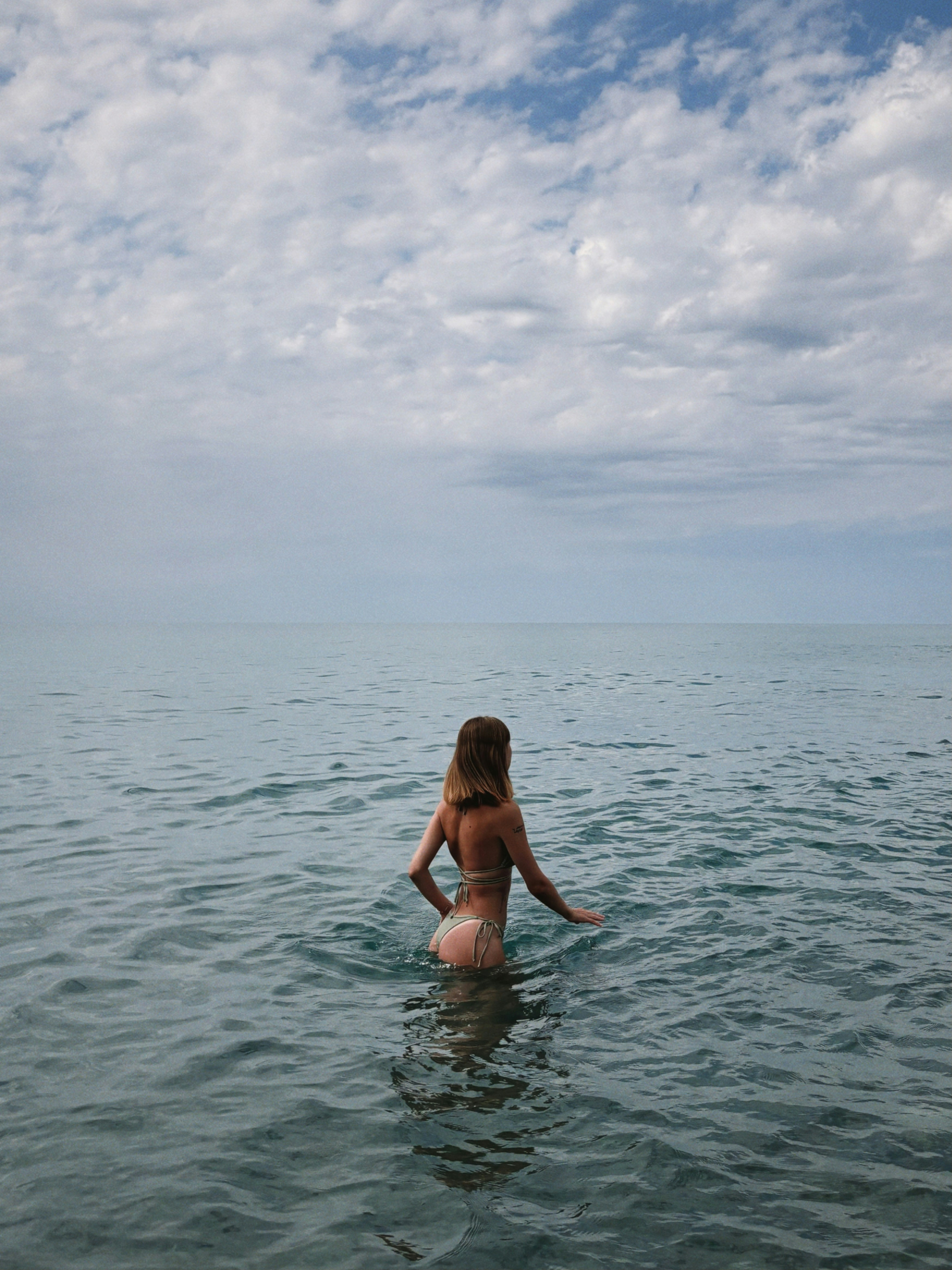 Une femme en bikini assise sur une planche de surf dans l’océan