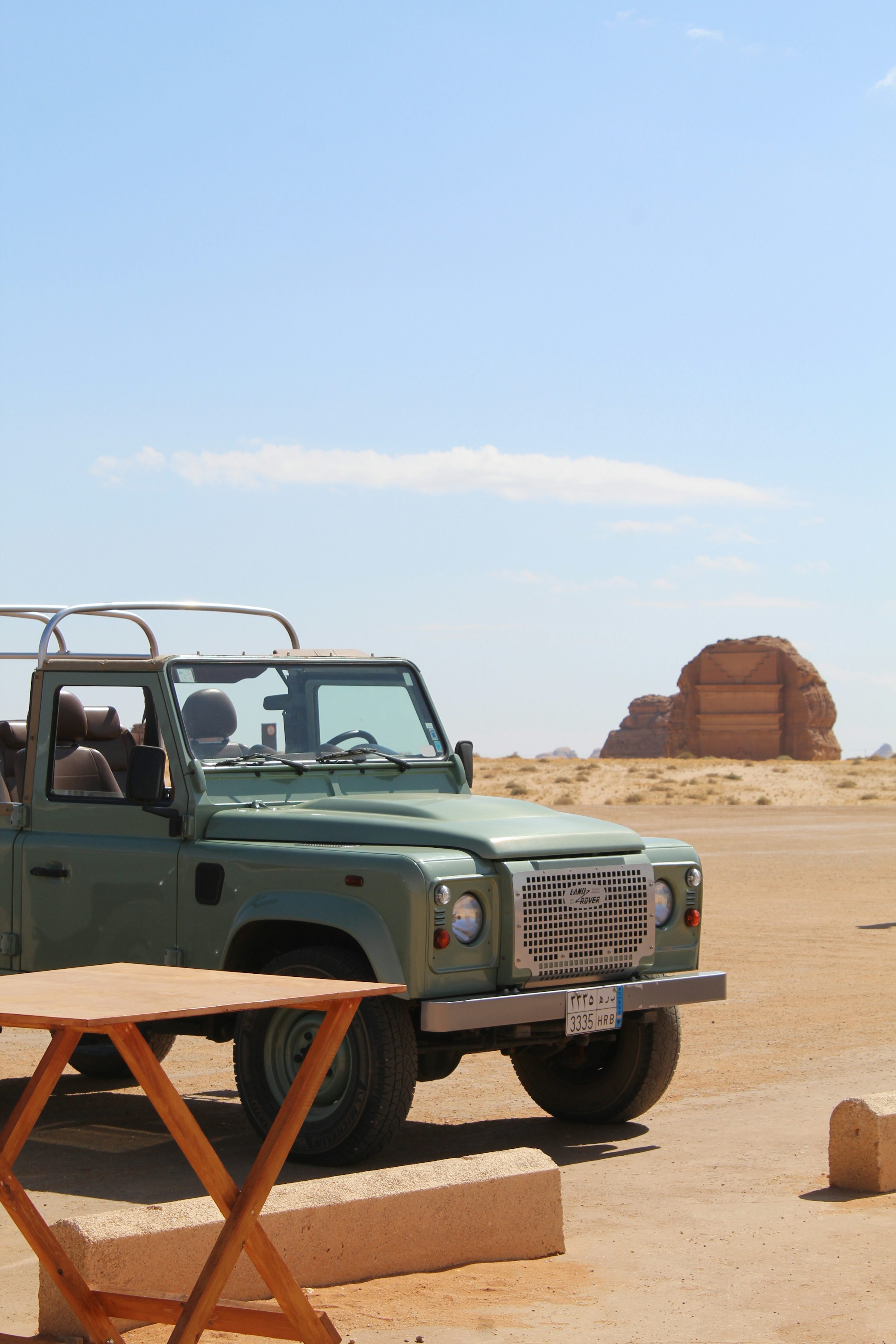 A green truck parked on top of a dirt field