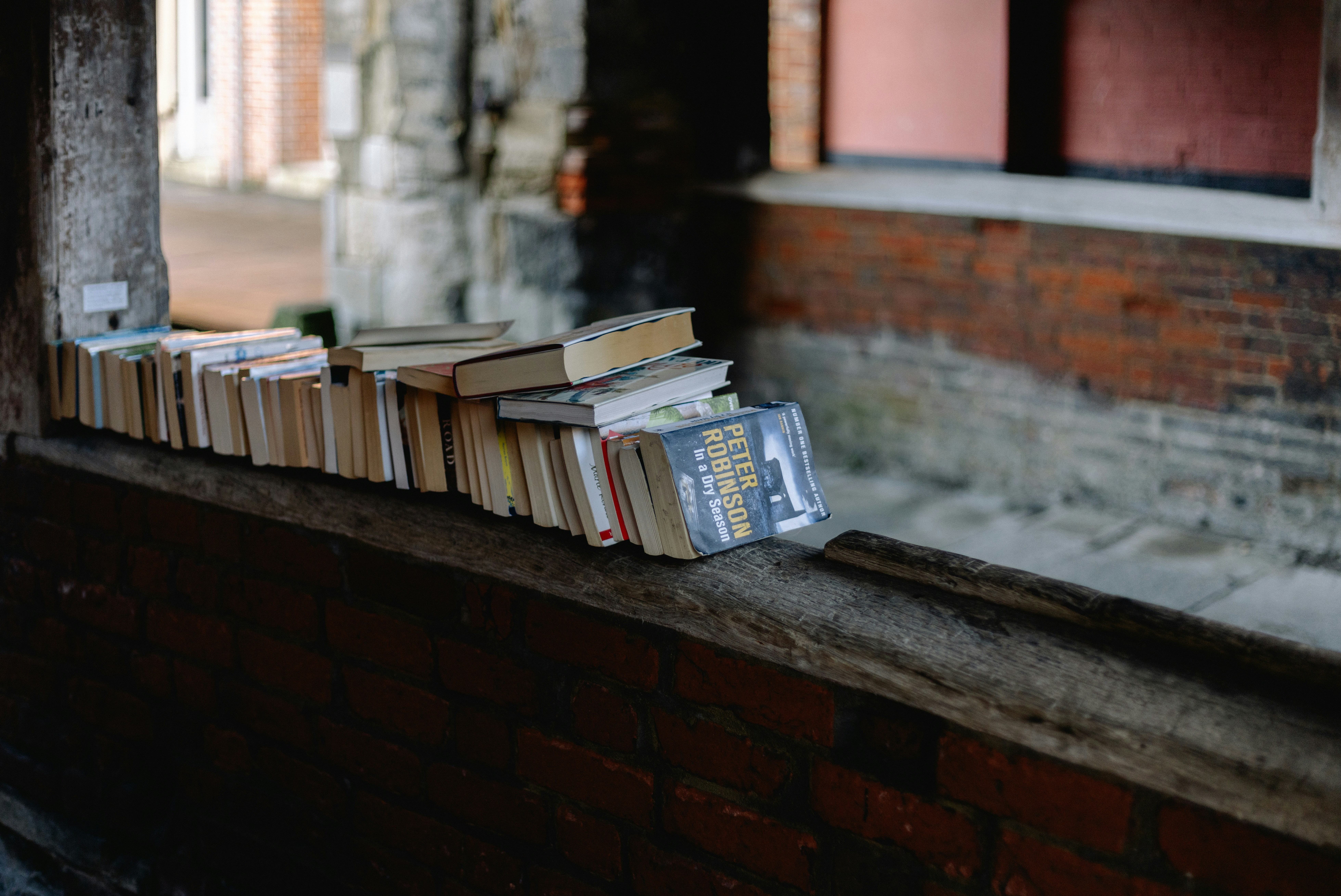 Une pile de livres posée sur le rebord d’une fenêtre
