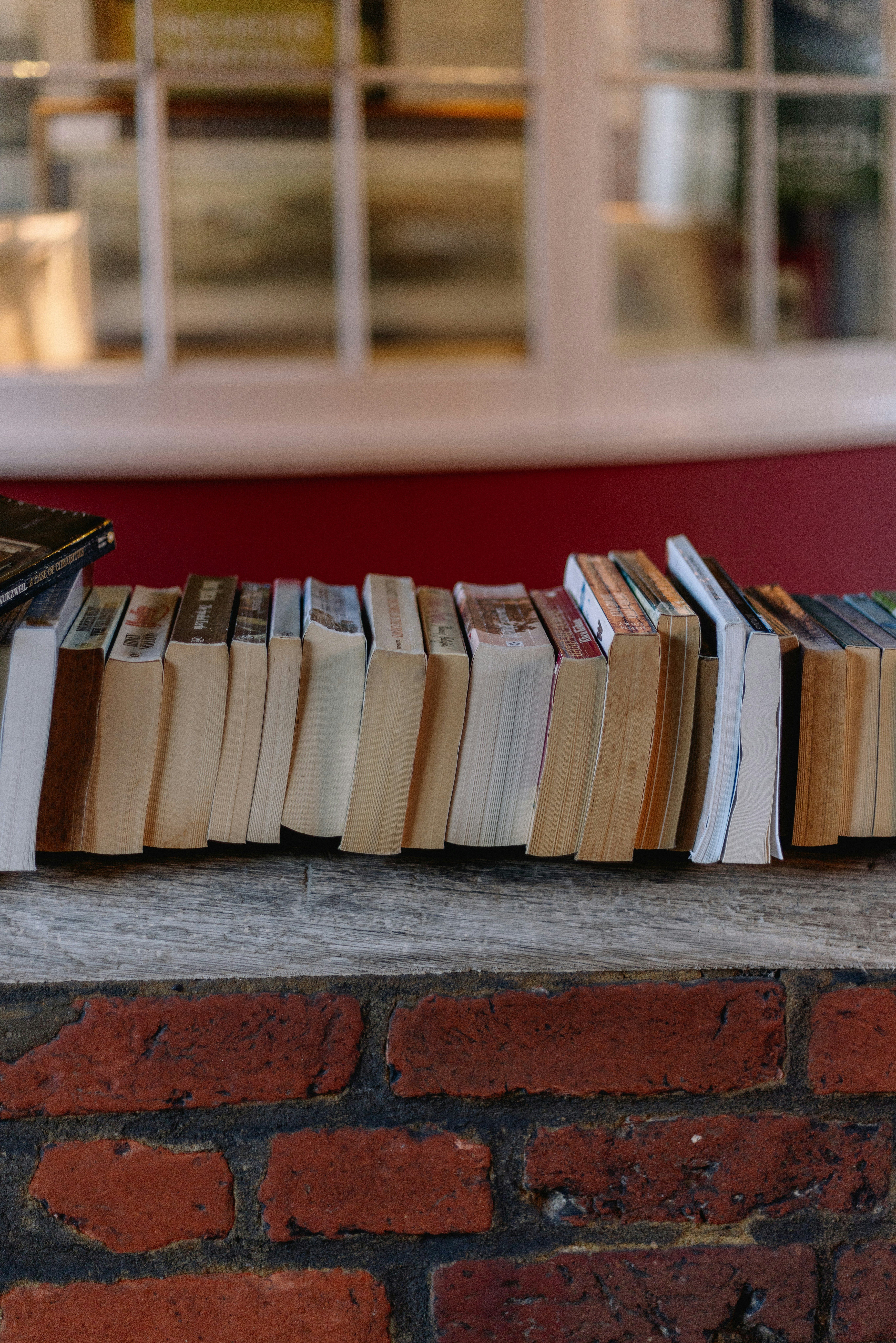 Une pile de livres posée au sommet d’un mur de briques