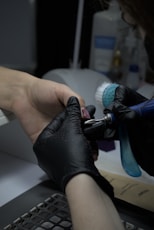 A person with a glove on is cleaning a keyboard
