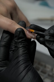 A person wearing black gloves and holding a cigarette