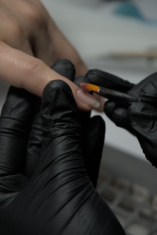 A person wearing black gloves and holding a cigarette