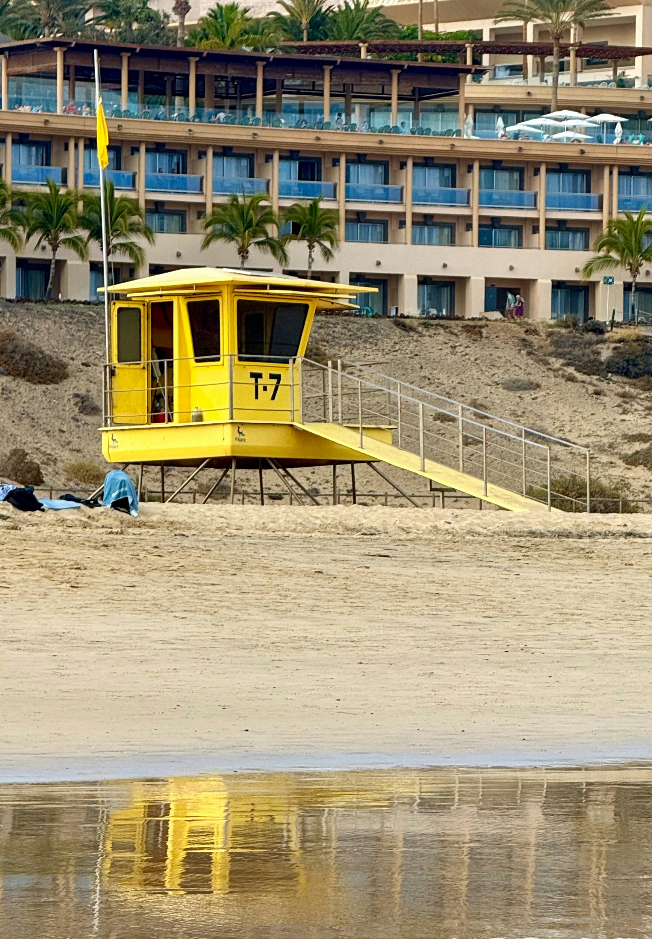 A yellow lifeguard tower sitting on top of a sandy beach