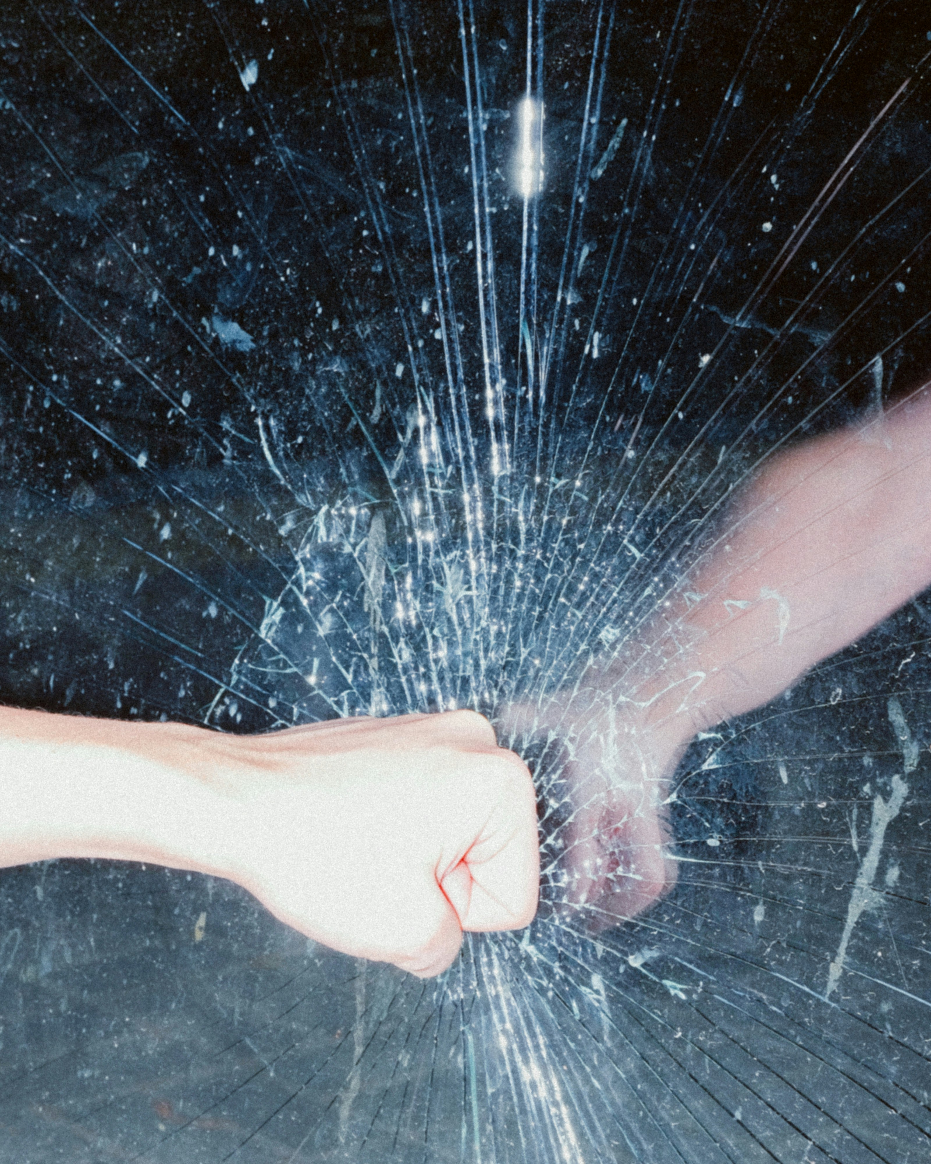 A hand holding a broken glass in the dark