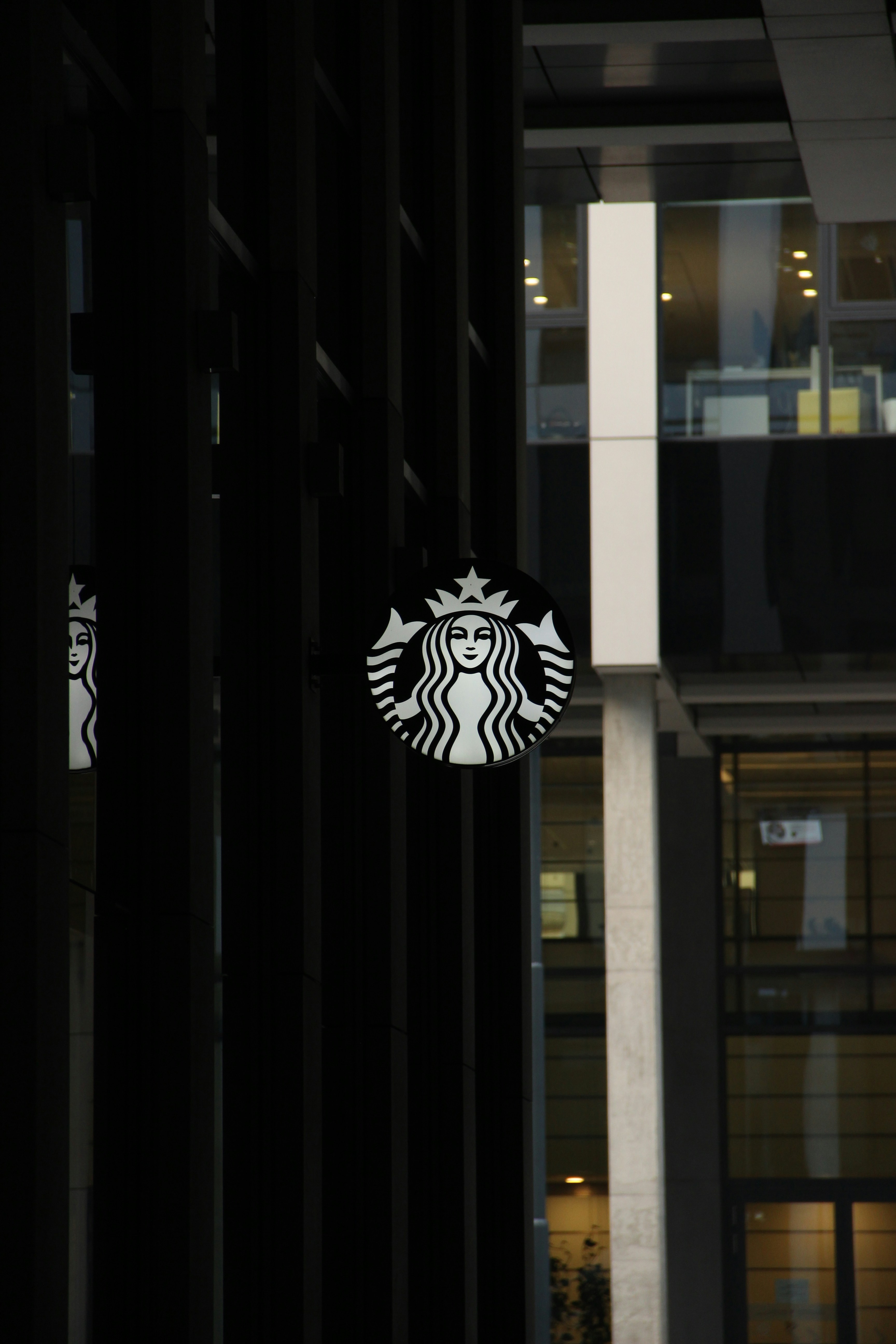 A starbucks sign hanging from the side of a building