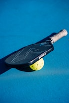 A close up of a tennis racket and a tennis ball