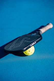 A close up of a tennis racket and a tennis ball