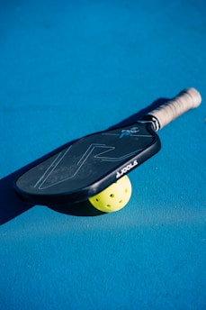 A close up of a tennis racket and a tennis ball