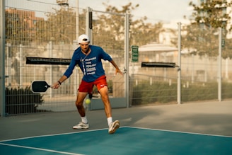 A man in blue shirt and red shorts playing a game of tennis