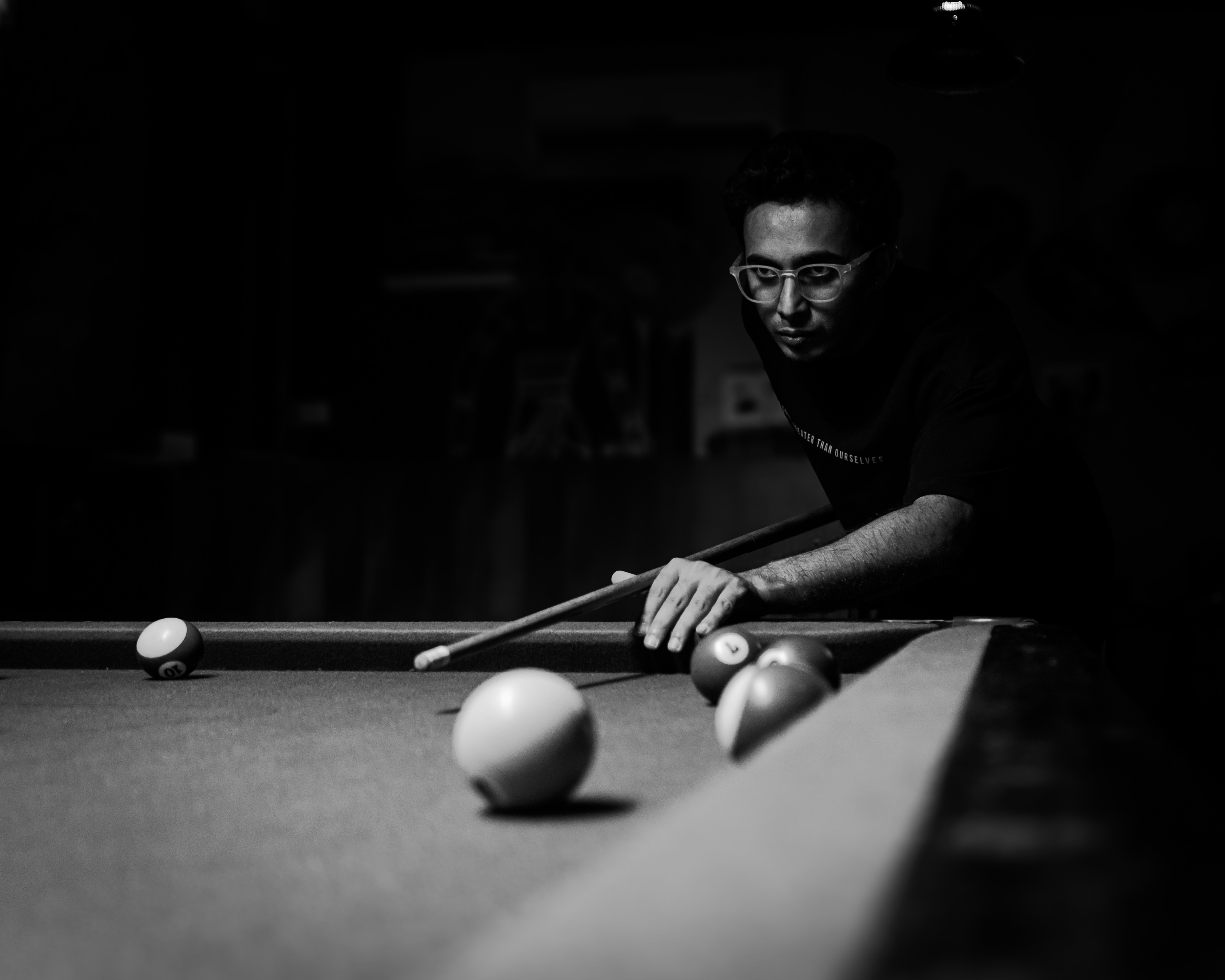 A man playing pool in a dark room
