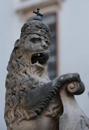 A statue of a lion with a bell on top of it