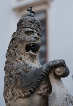 A statue of a lion with a bell on top of it