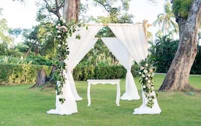 An outdoor wedding setup with white drapes and flowers
