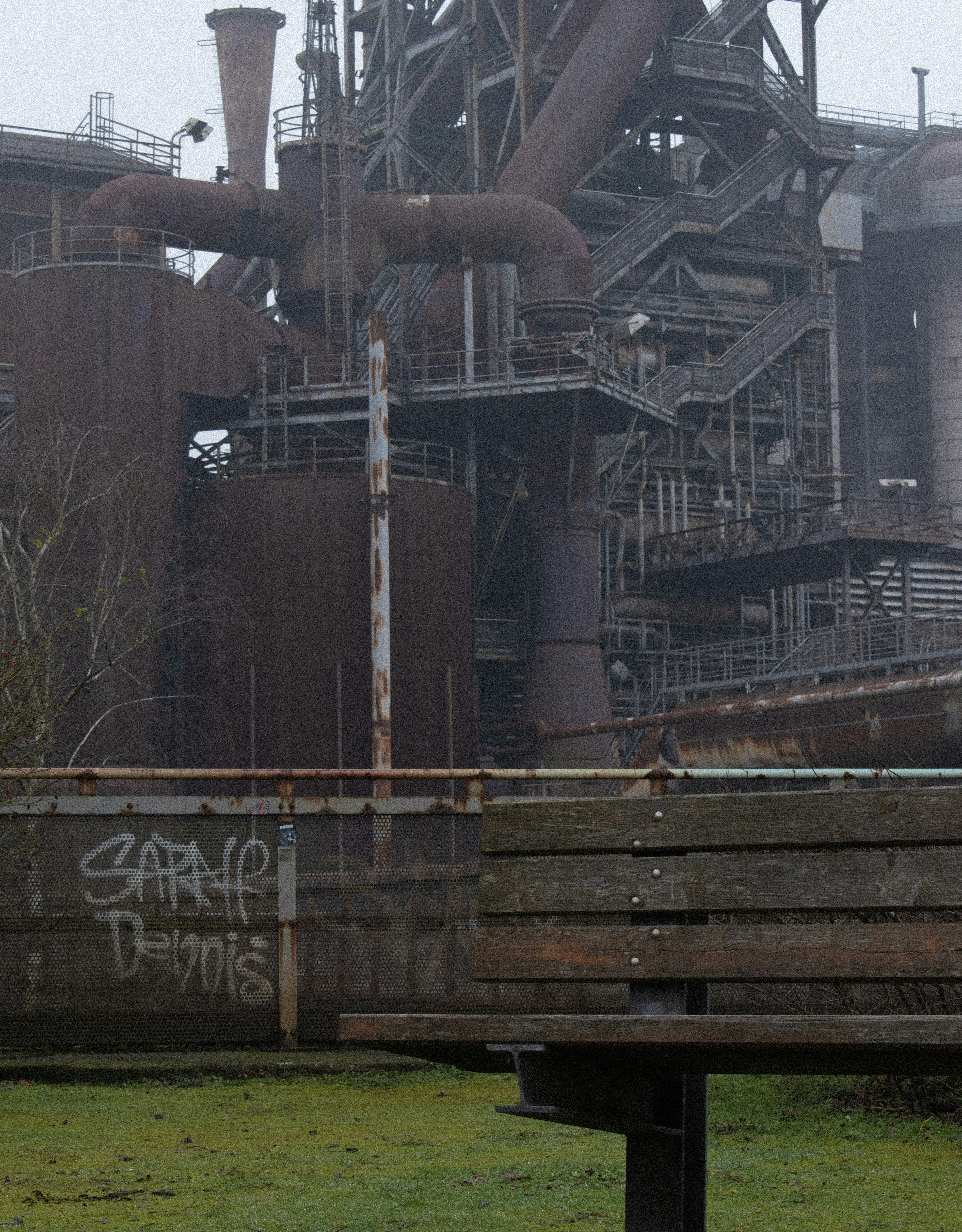 A bench sitting in front of a large factory