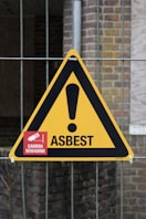 A yellow and black warning sign on a fence