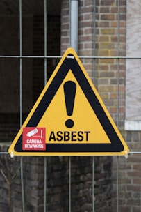 A yellow and black warning sign on a fence