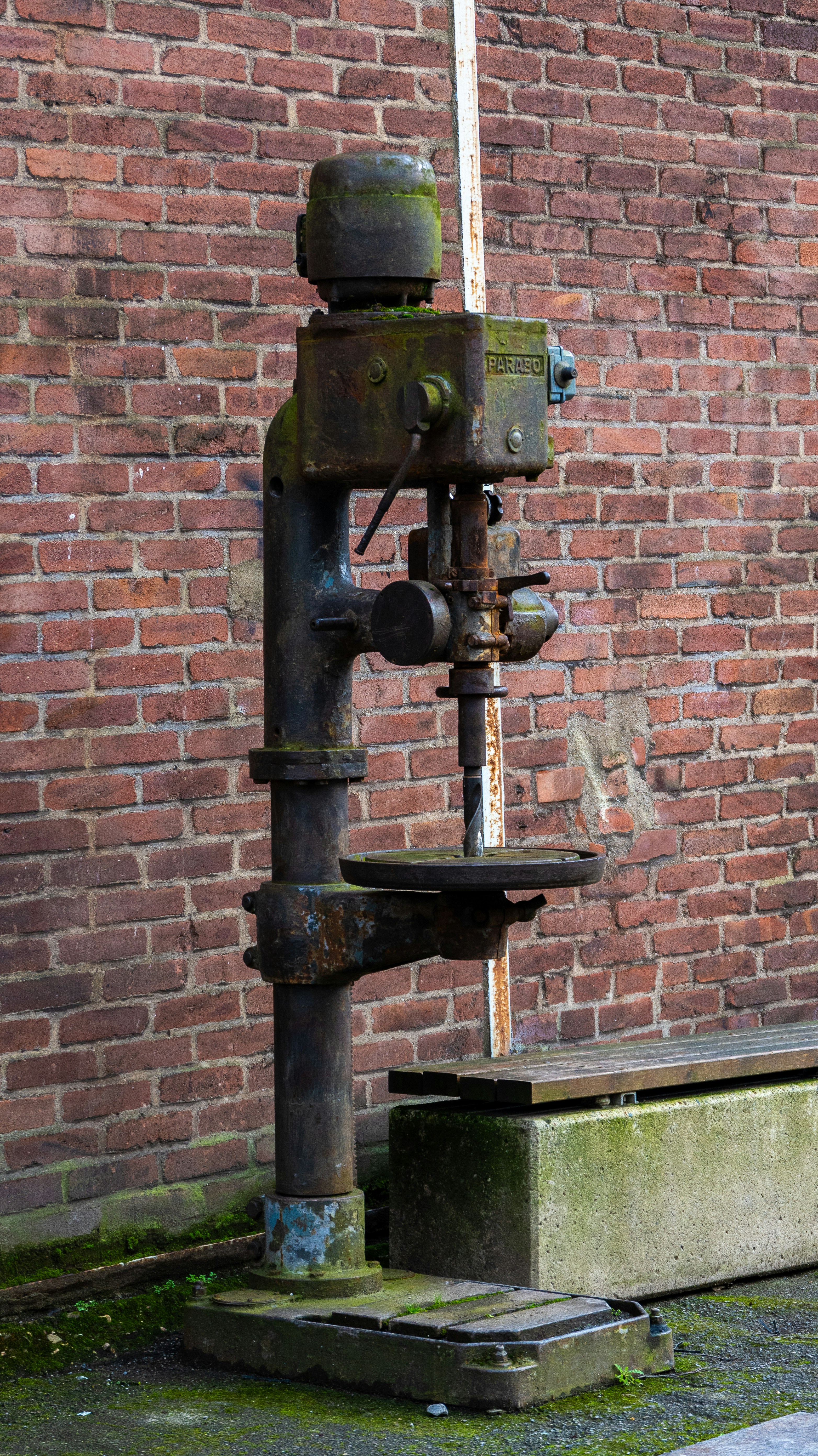 An old water pump in front of a brick wall