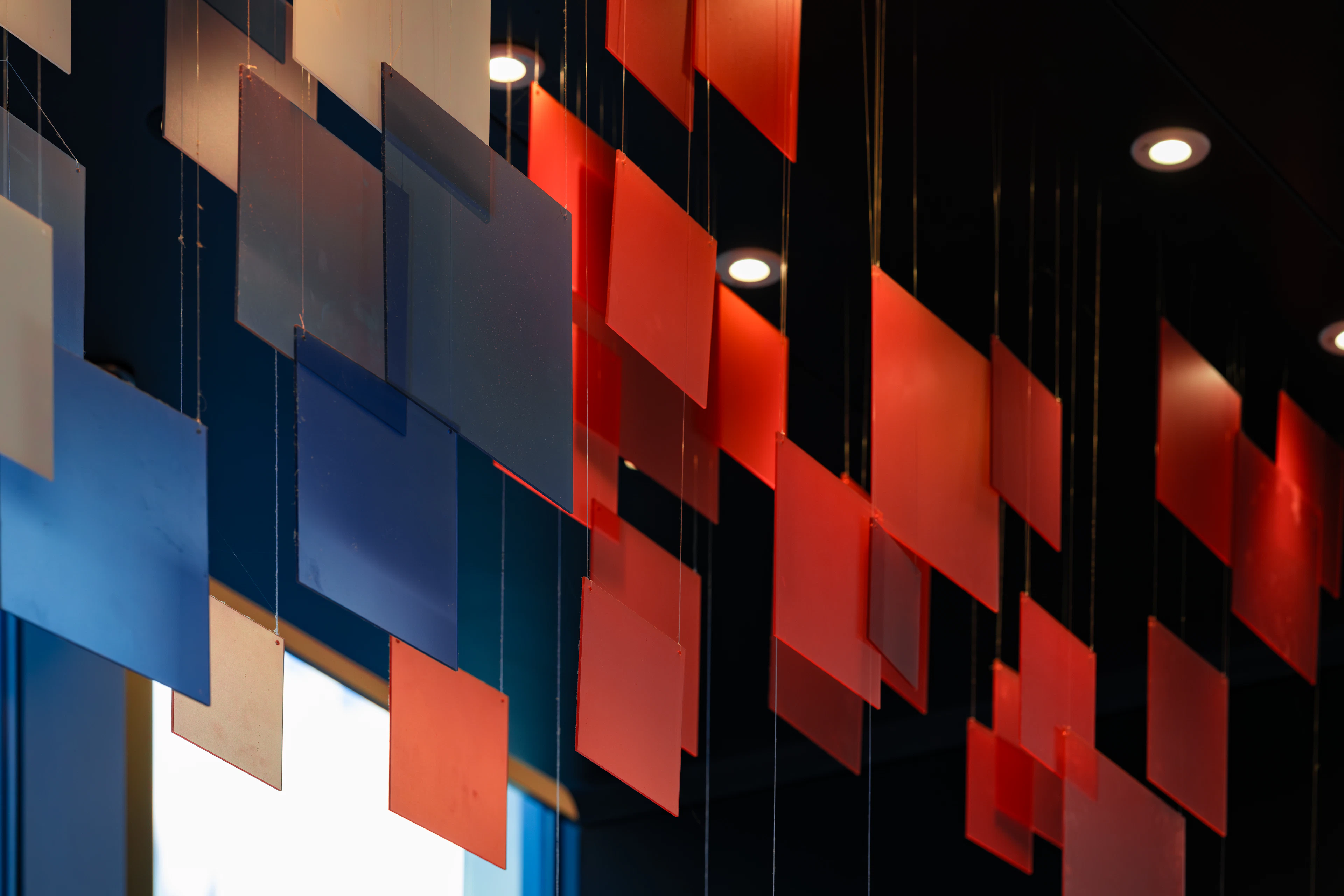 Coloured acoustic panels suspended below a ceiling