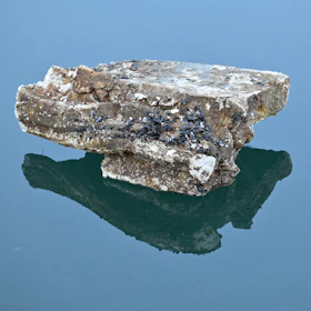 A rock sitting on top of a body of water