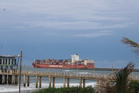 A large cargo ship in the ocean near a pier