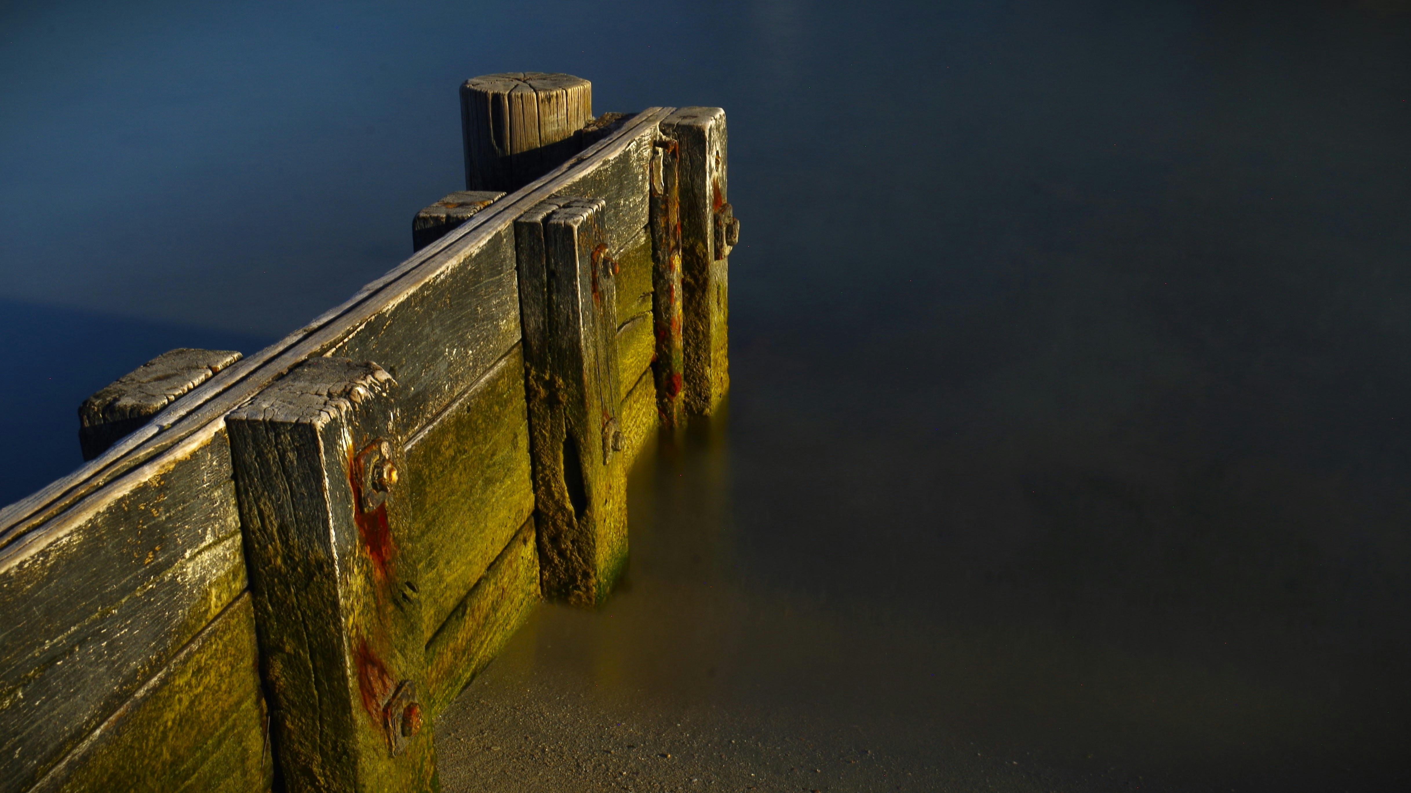 A long wooden dock with a bird perched on top of it