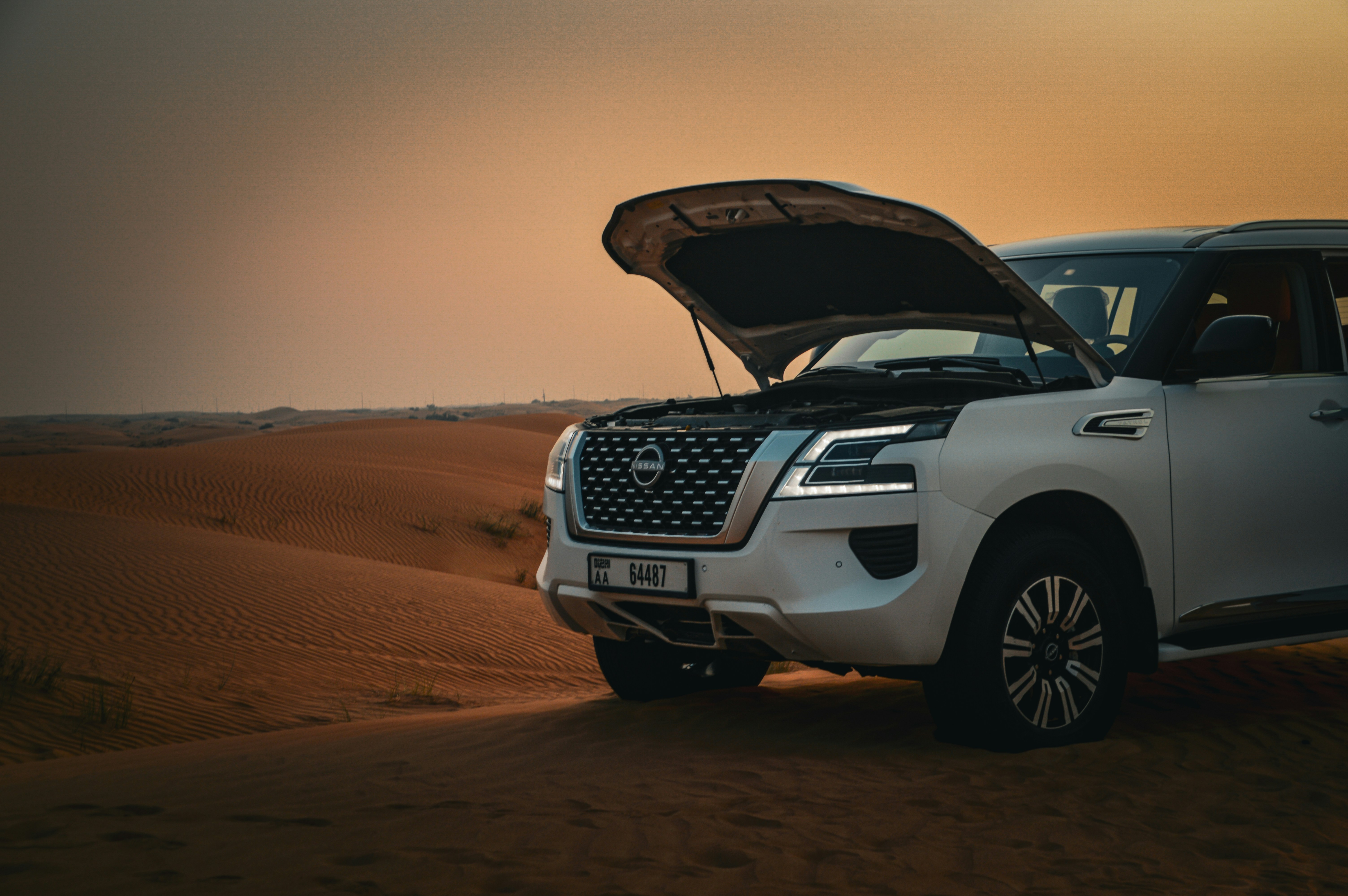 A white suv with its hood open in the desert