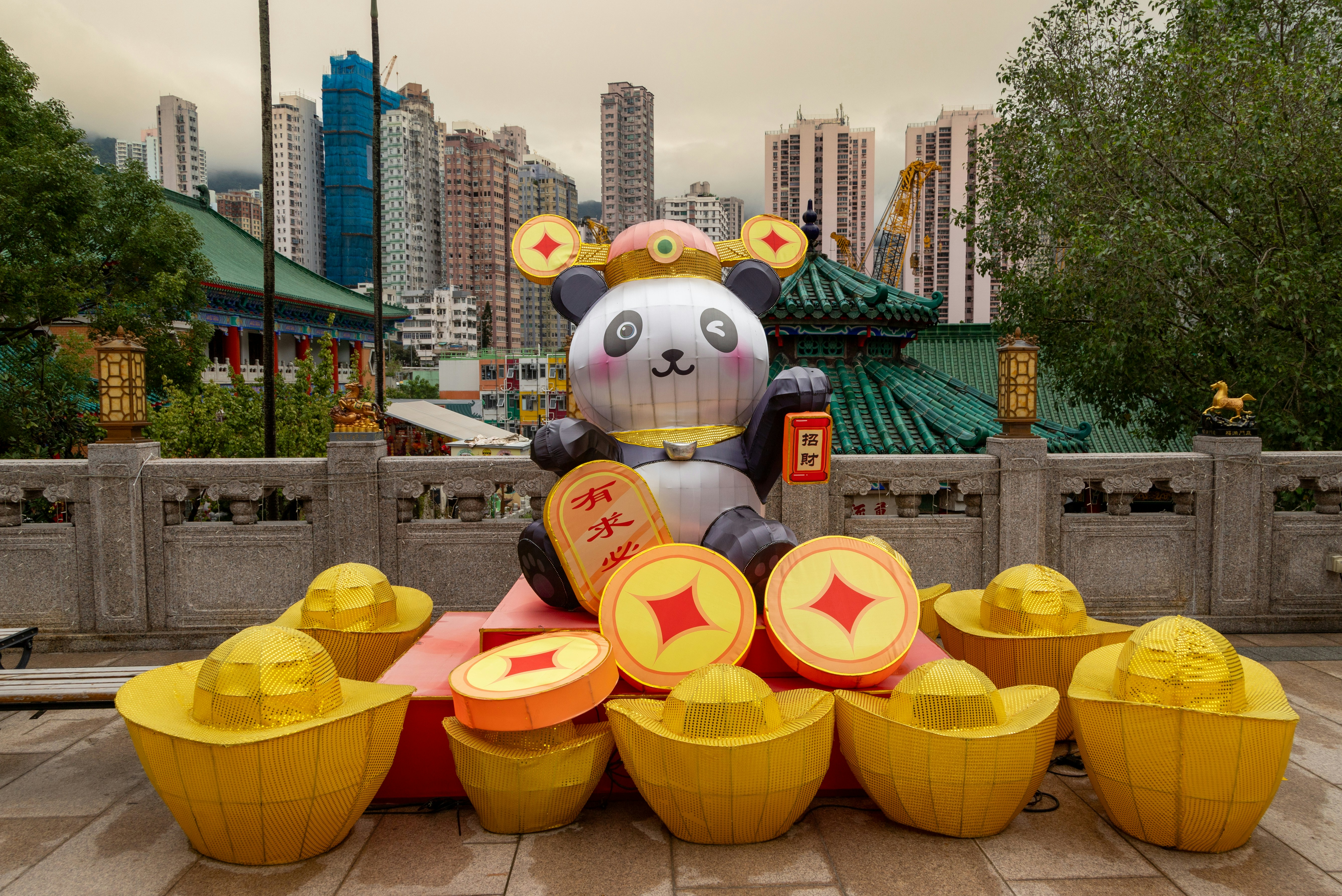 A statue of a panda bear sitting on top of a pile of cupcakes