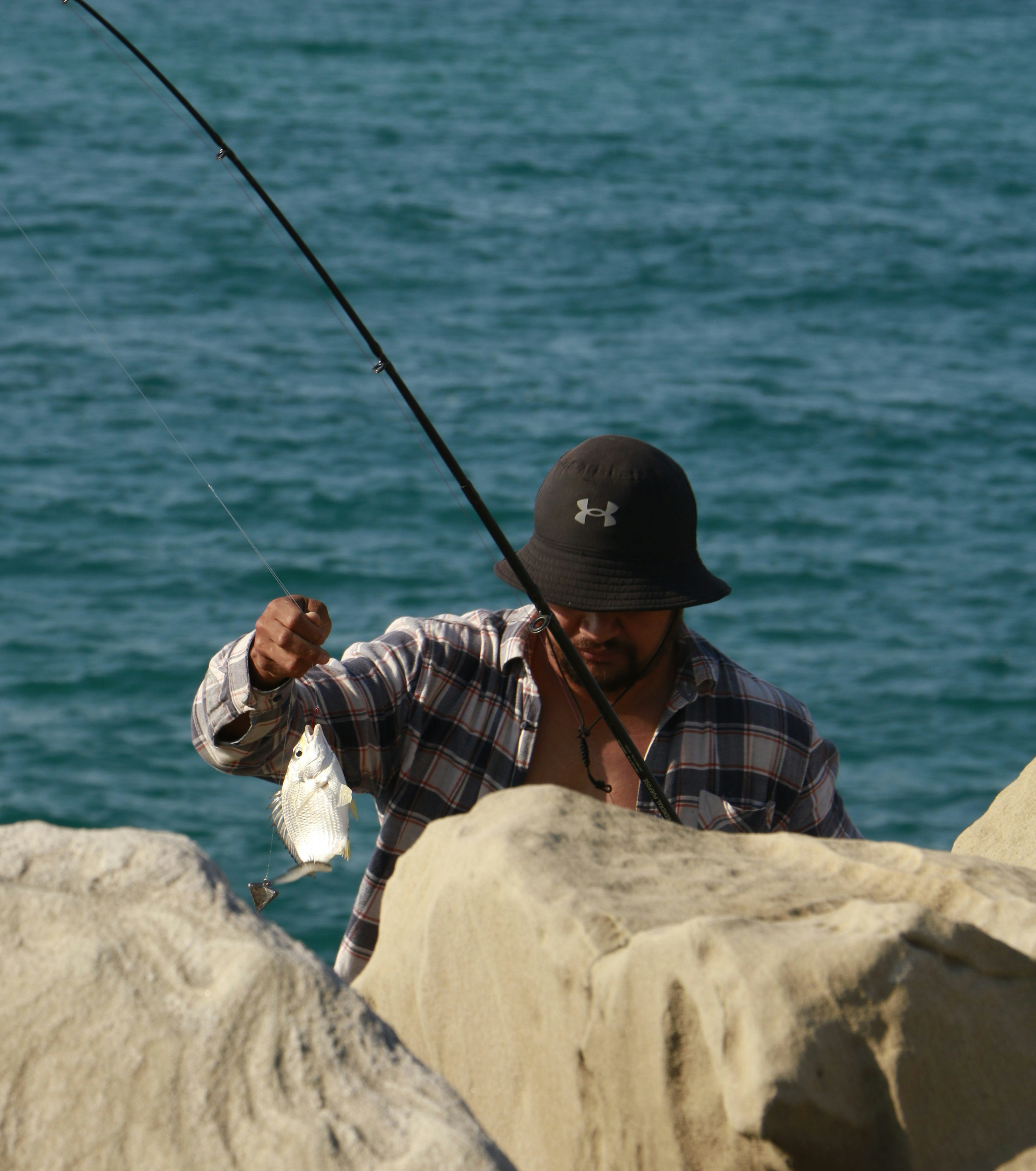 A man standing on a rock with a fishing rod