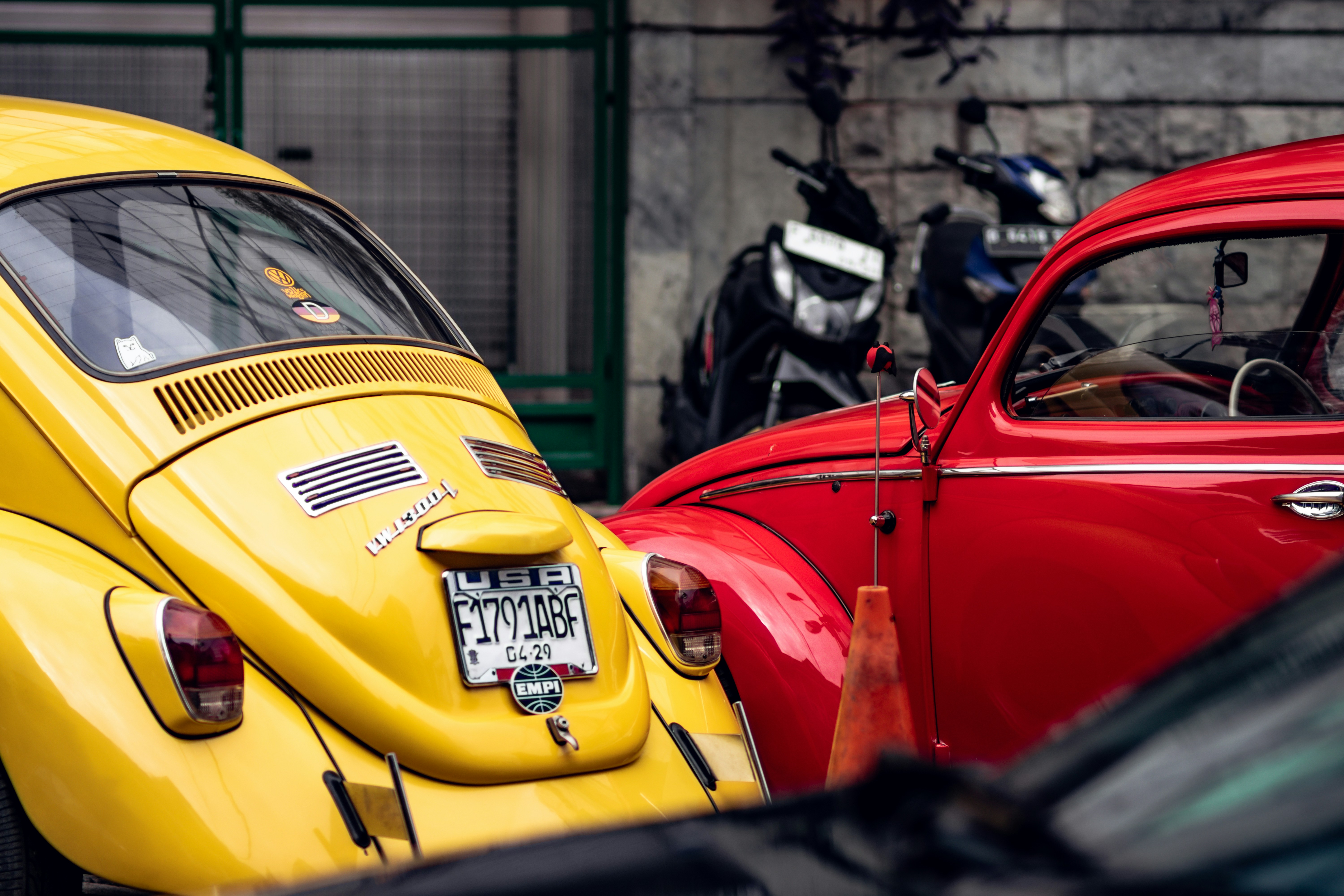 A yellow vw bug parked next to a red vw bug