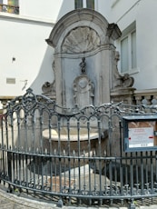 An iron fence surrounding a fountain in front of a building