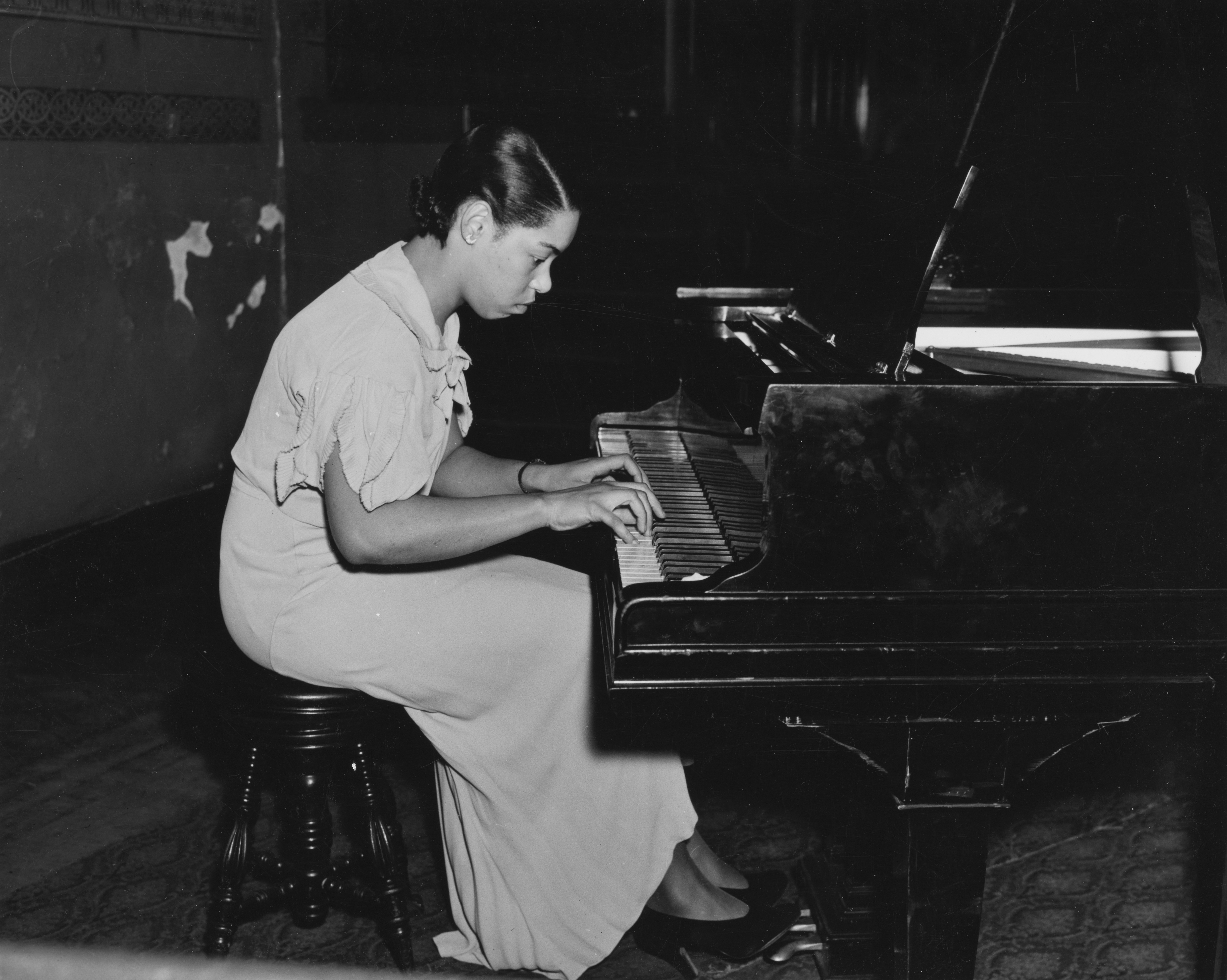 A woman playing a piano in a dimly lit room.