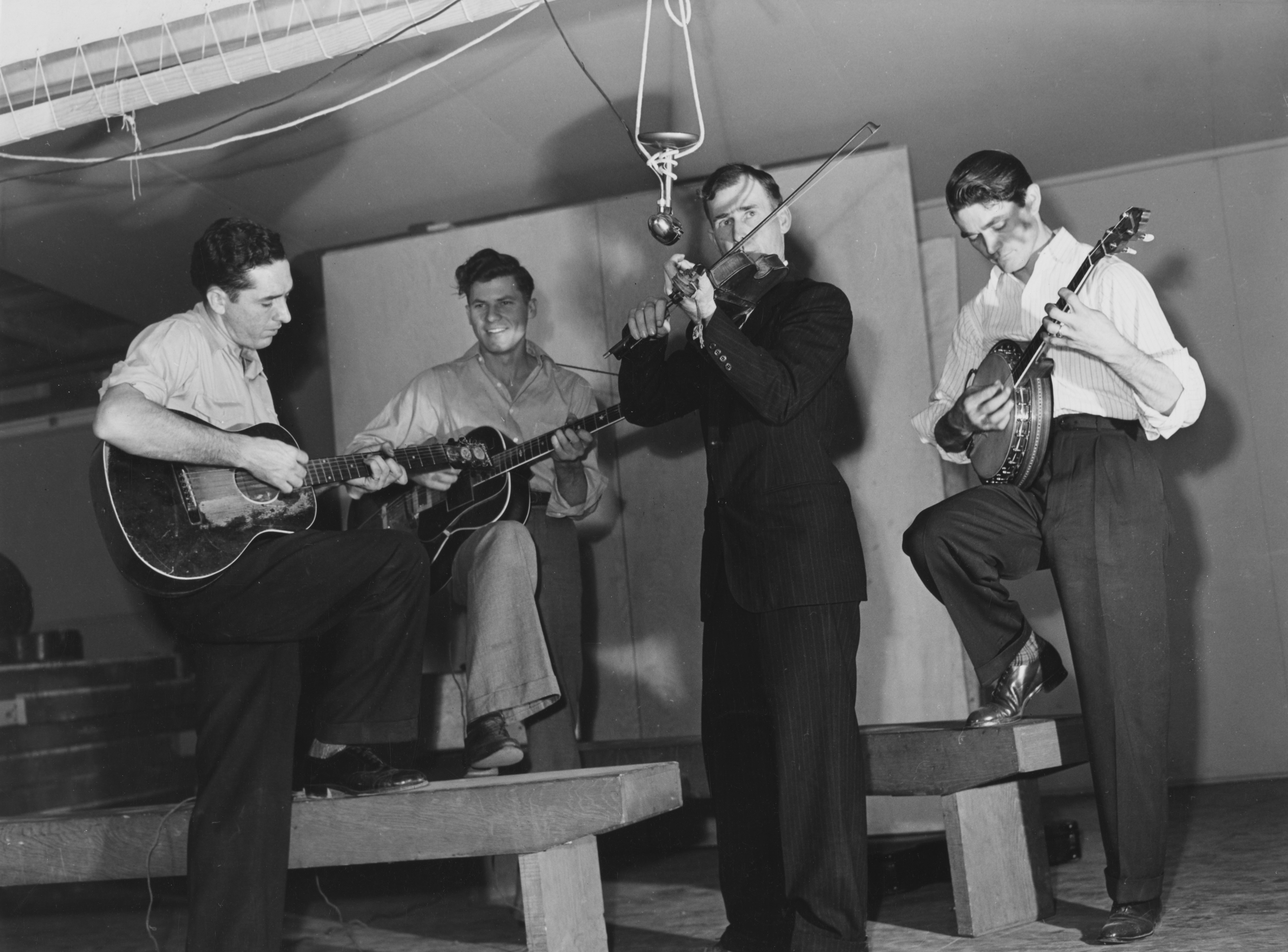 Four musicians playing string instruments on a stage. photo – Free Film ...