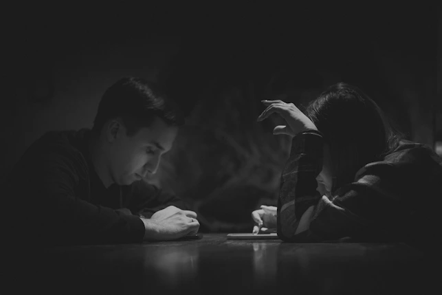 A man sitting at a table writing on a piece of paper
