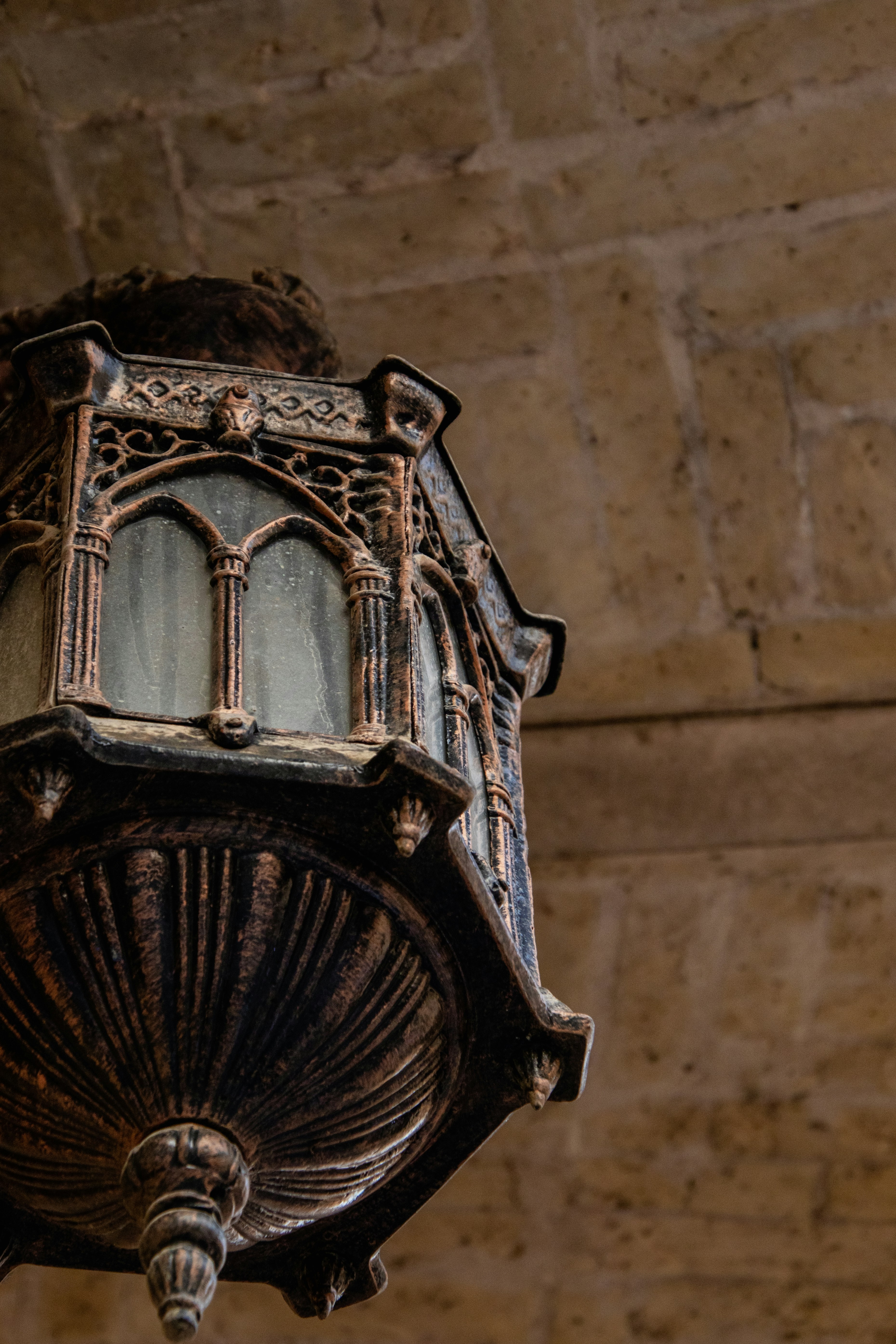 An old fashioned street light hanging from a brick wall