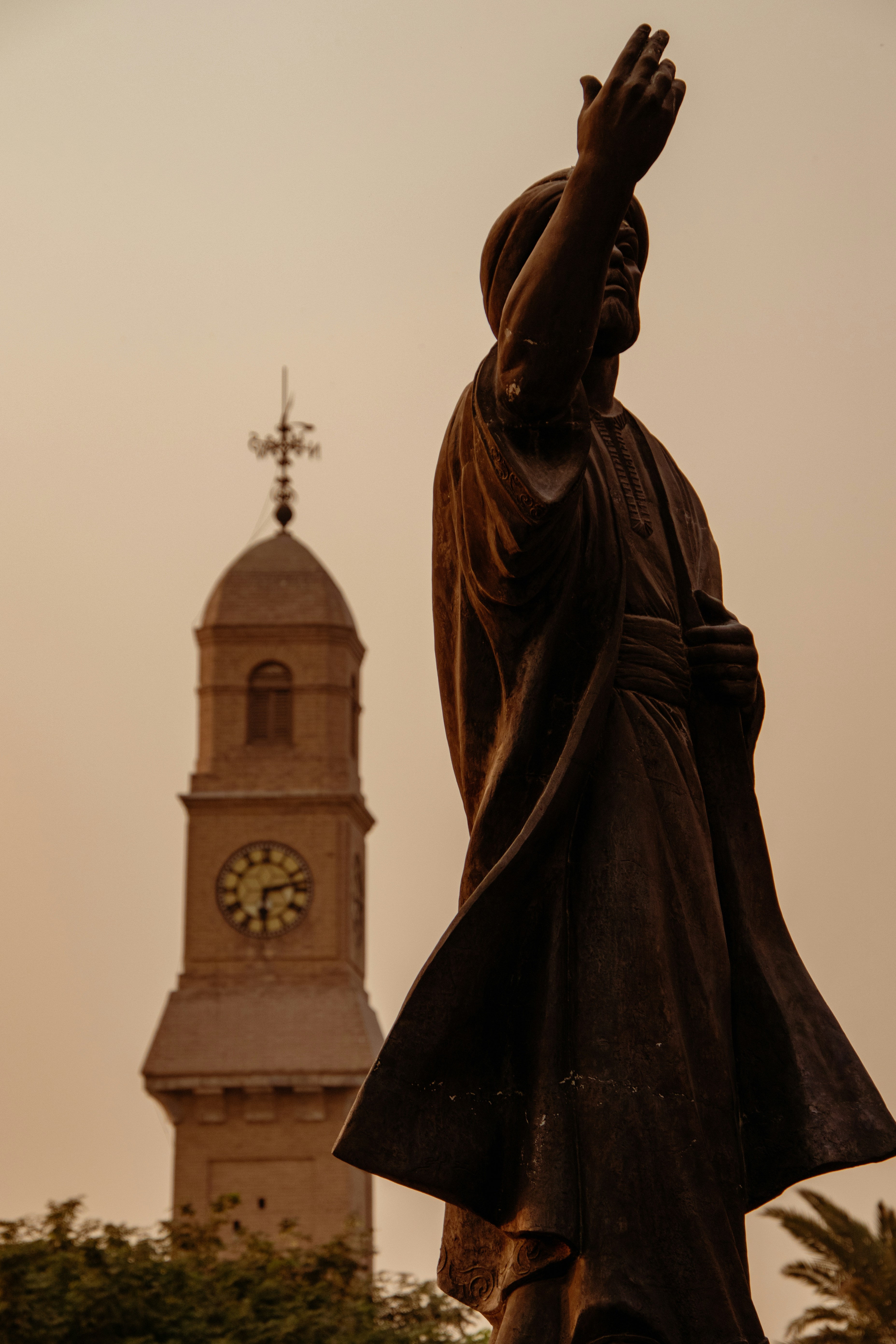 Uma estátua em frente a uma torre do relógio