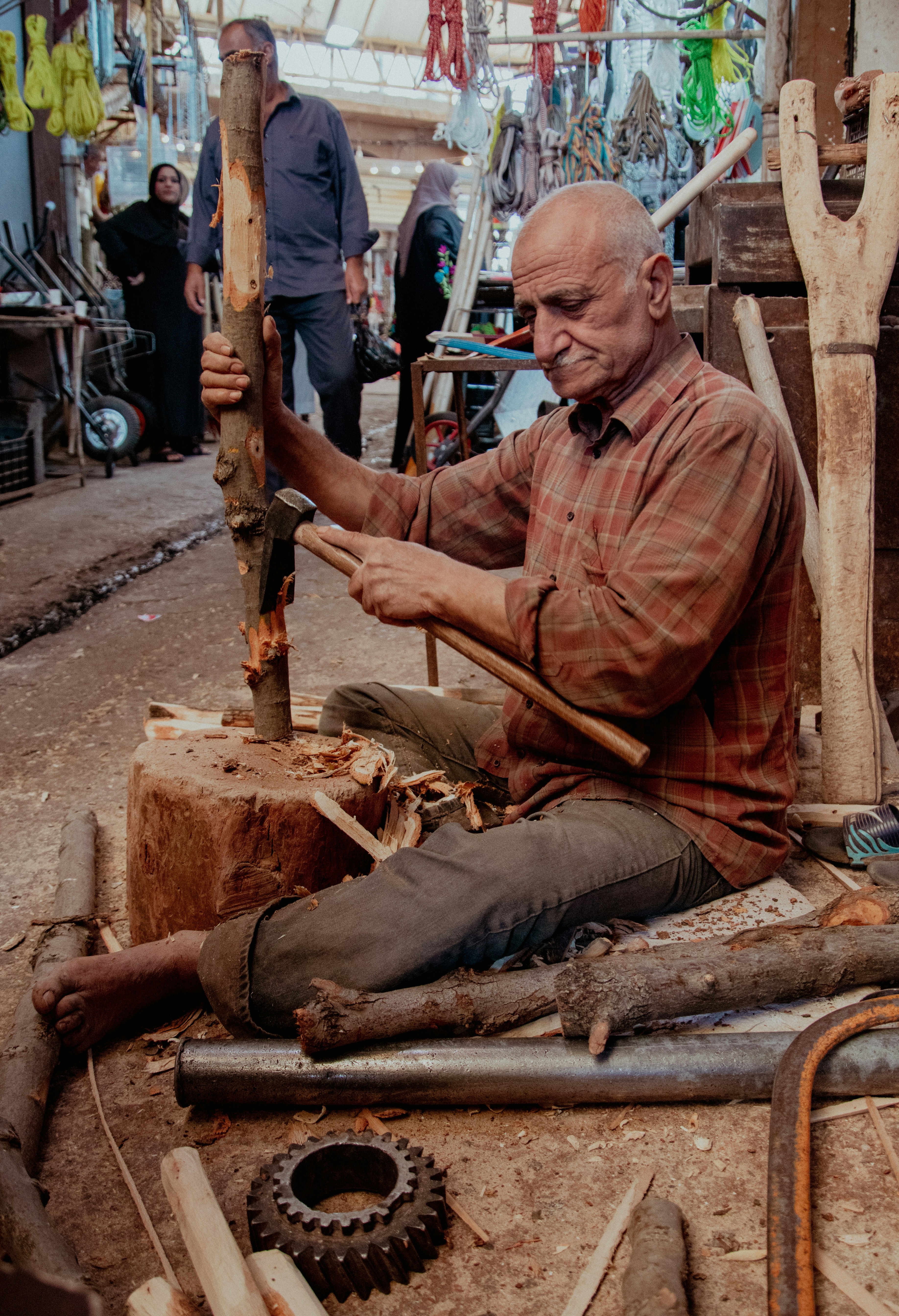 A man sitting on the ground working on a piece of wood