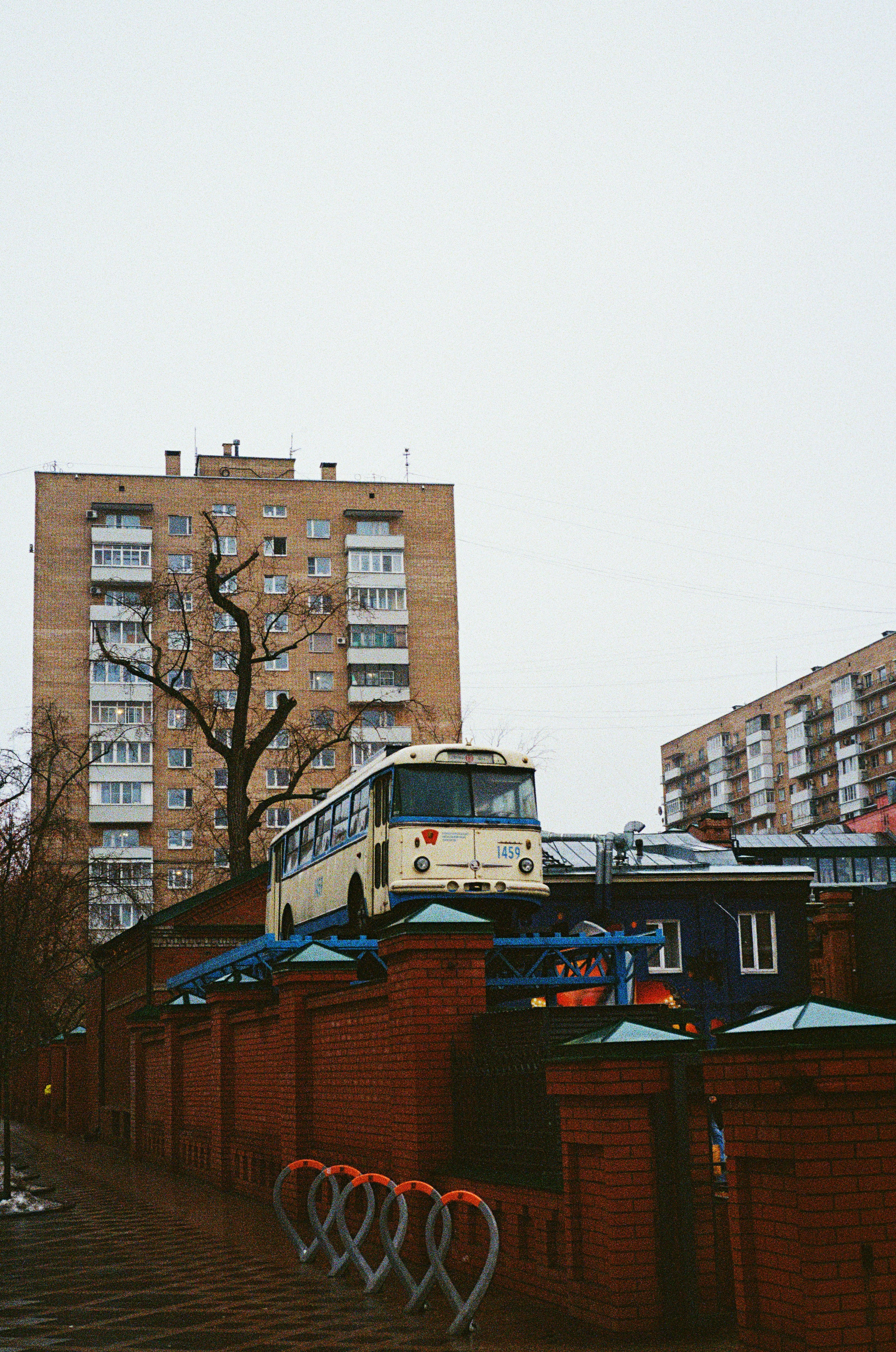 A white bus driving down a street next to tall buildings