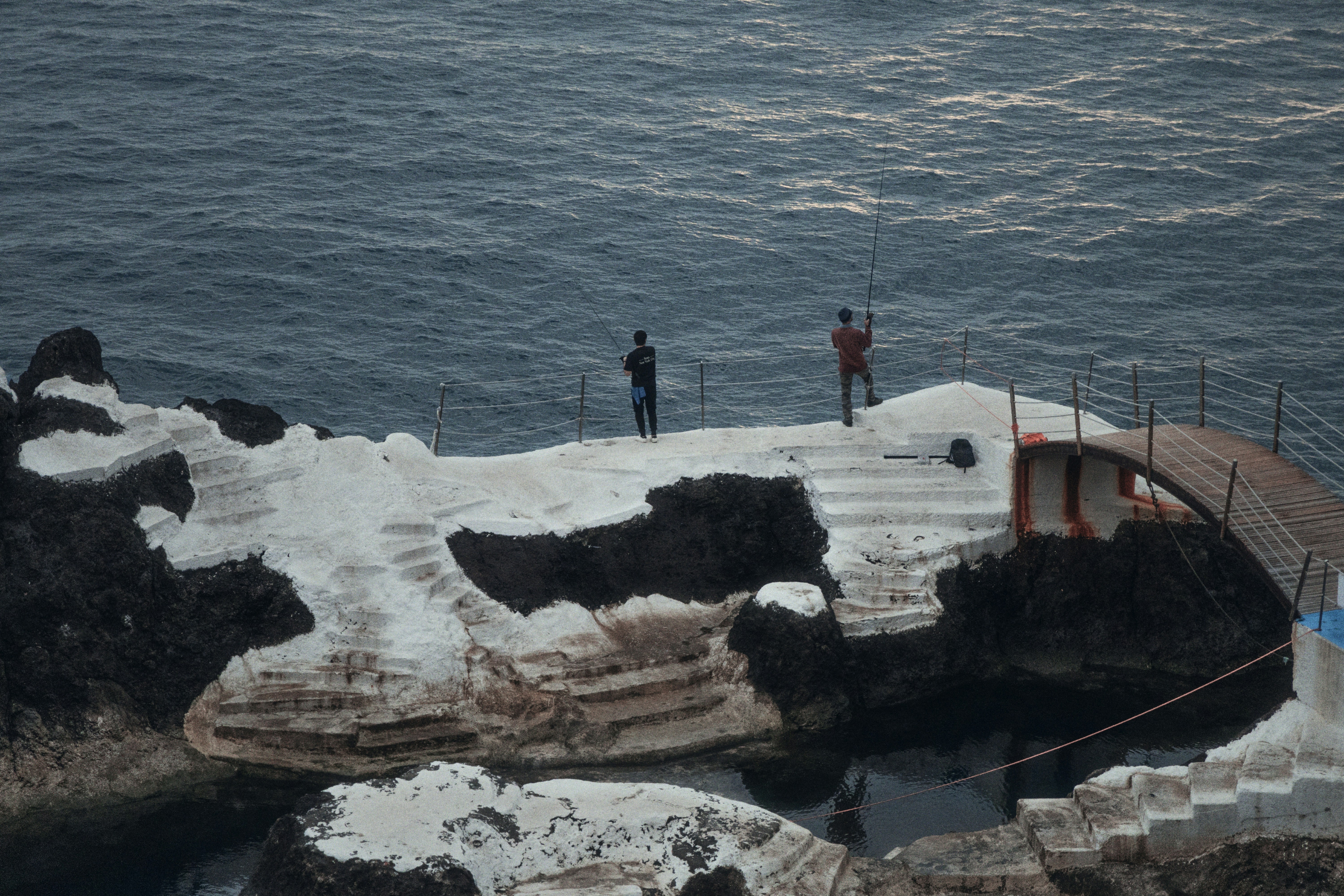 A group of people standing on top of a cliff next to the ocean