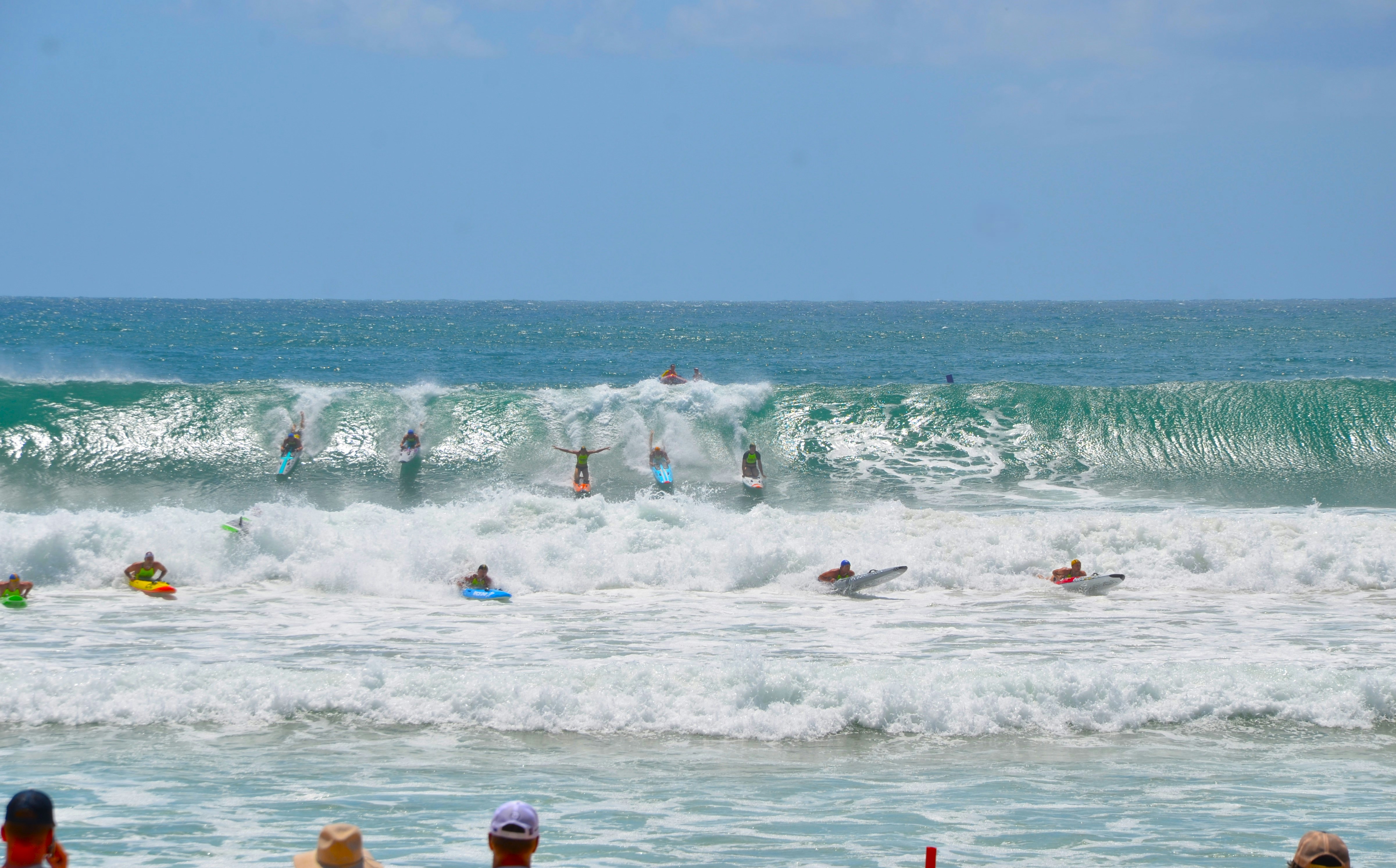 A group of people standing on top of a beach next to the ocean