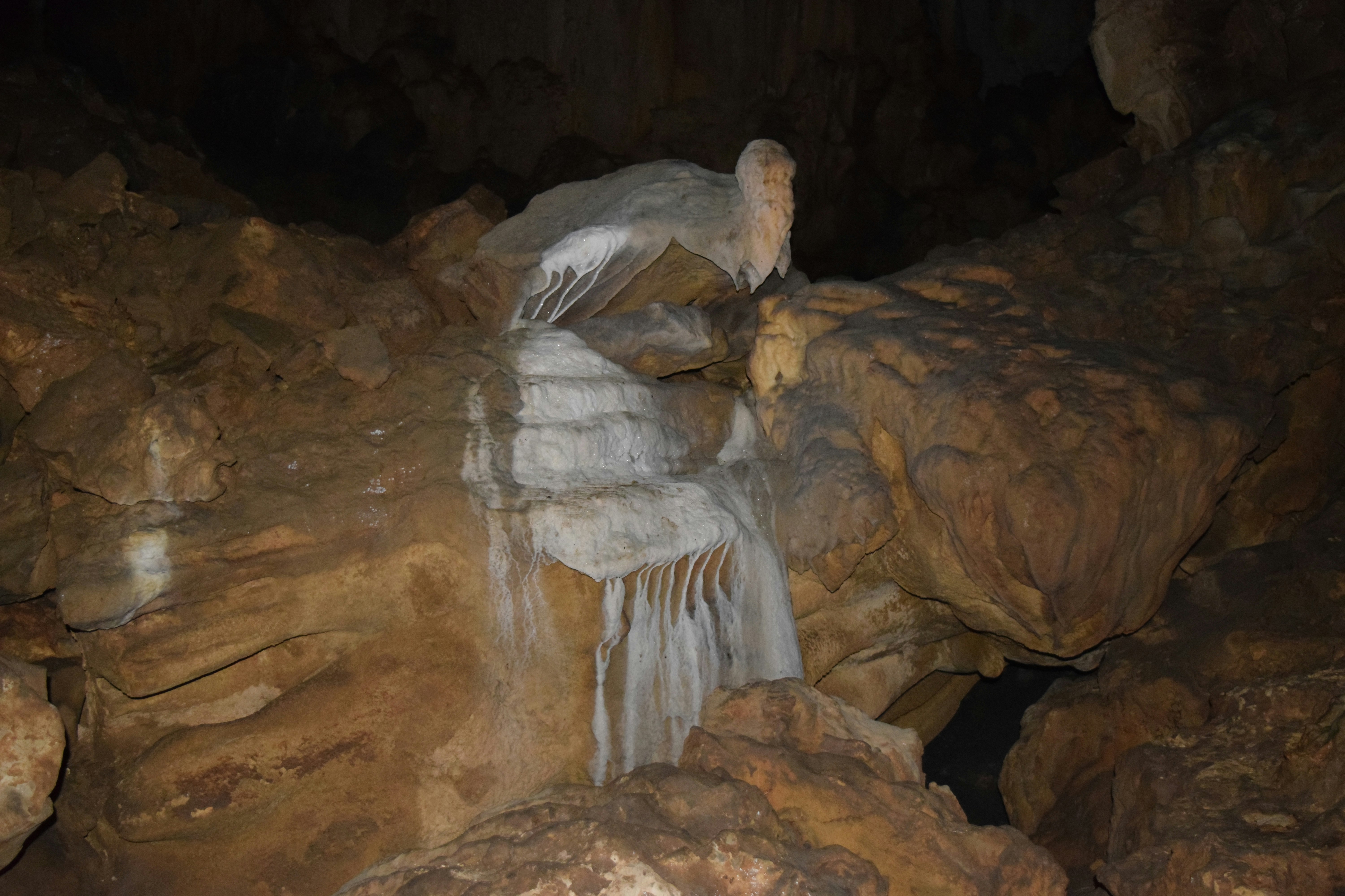 A man standing in a cave next to a waterfall