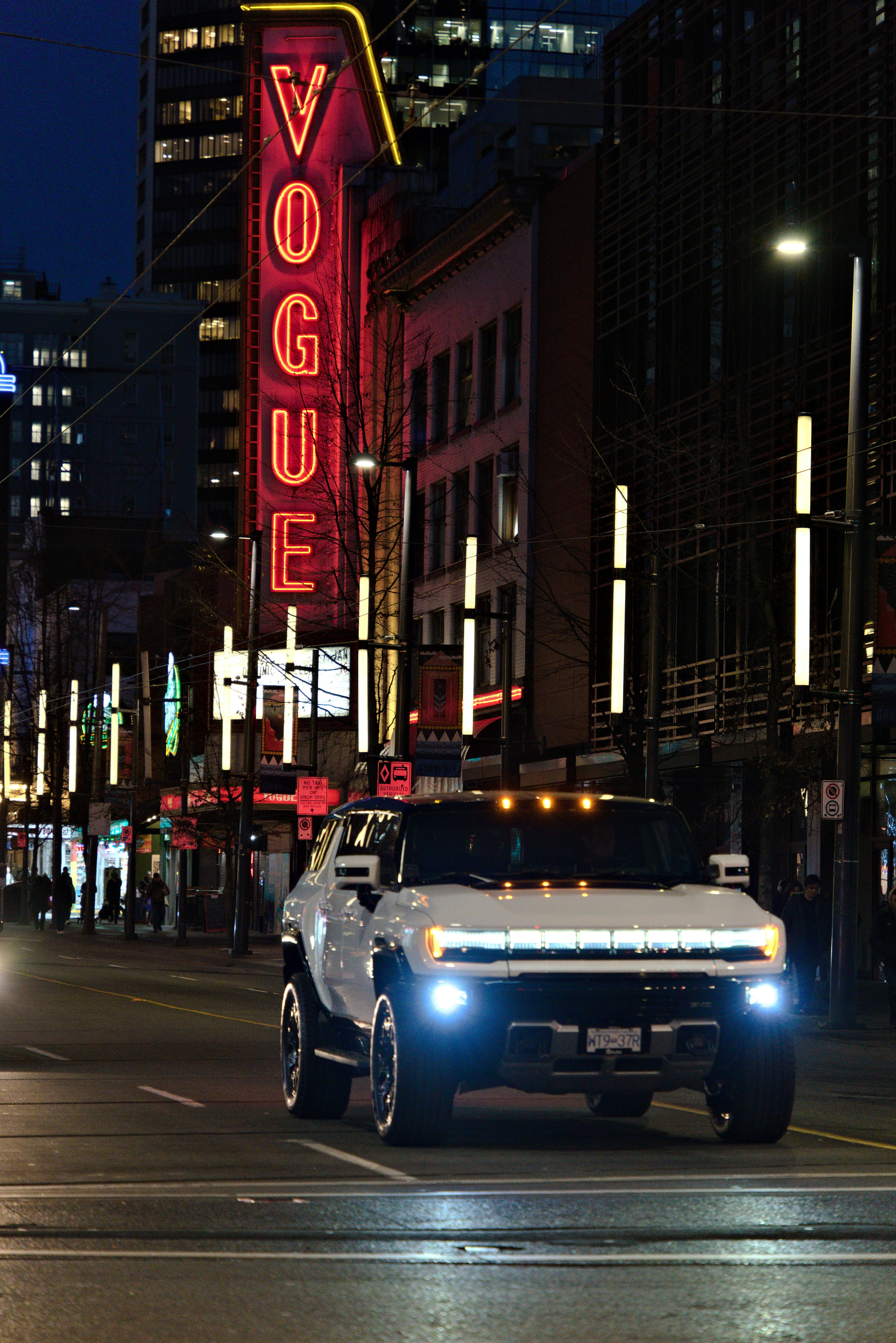 A white truck driving down a street next to tall buildings