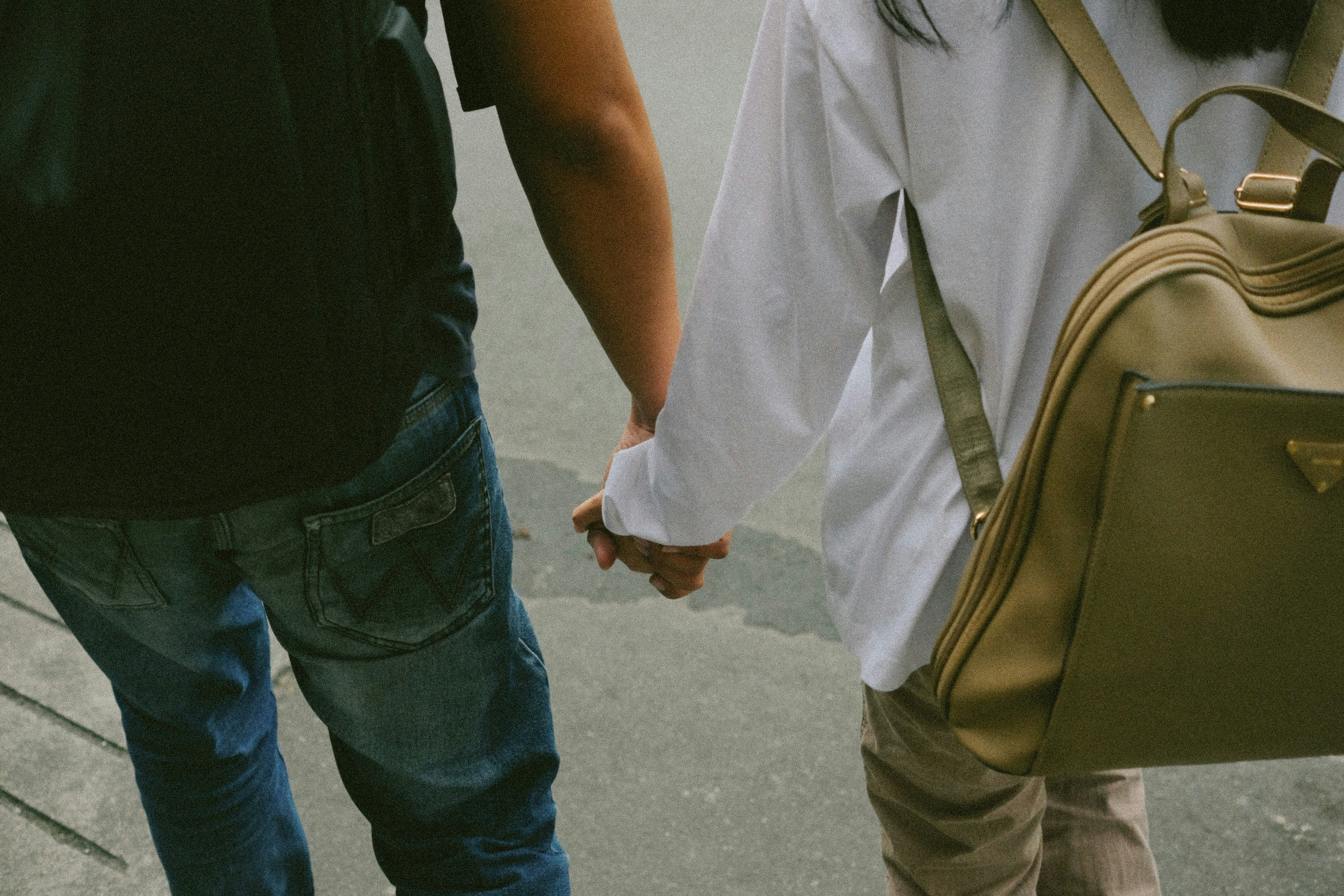 A man and a woman walking down a street holding hands