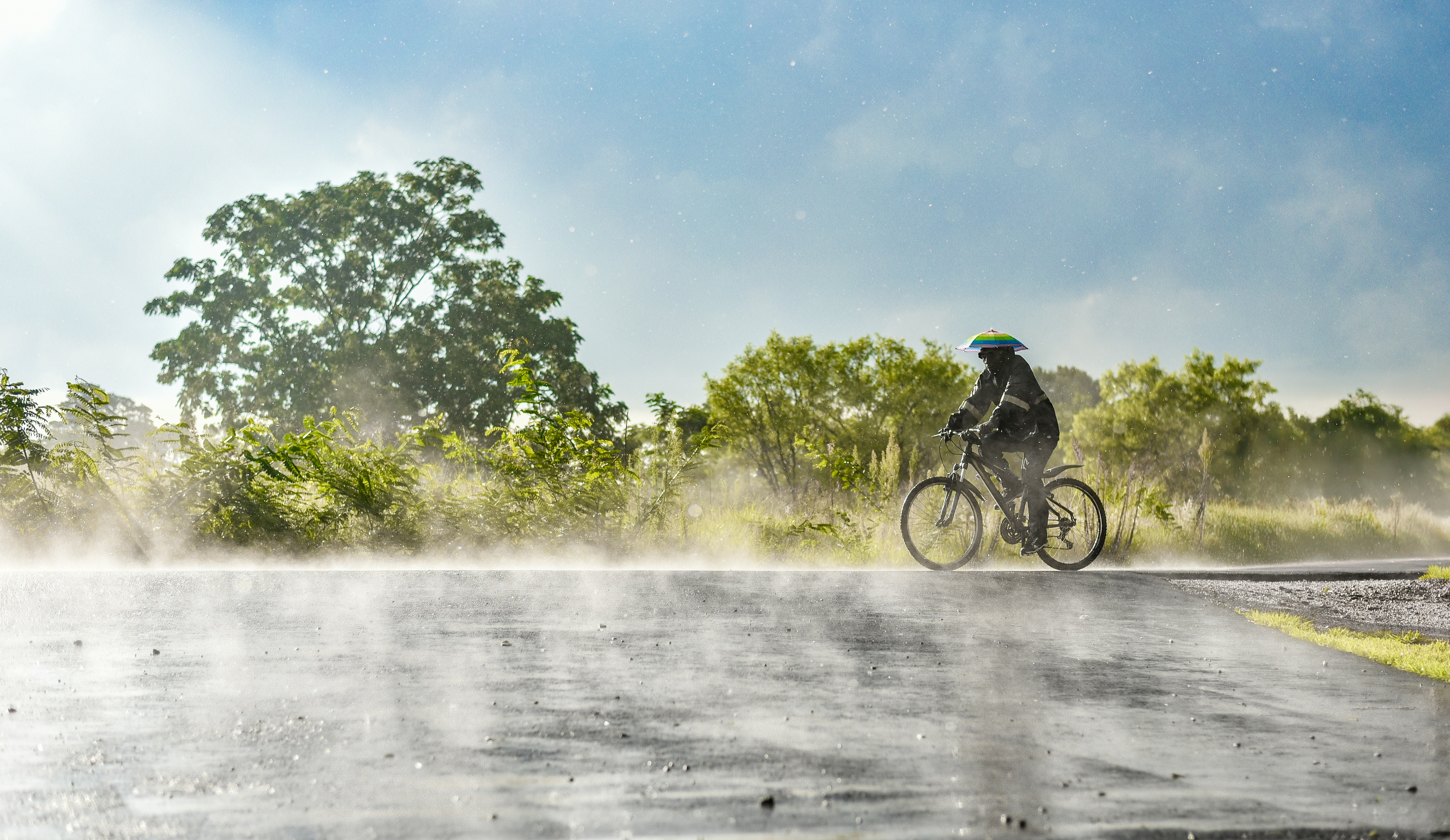 A man riding a bike down a wet road