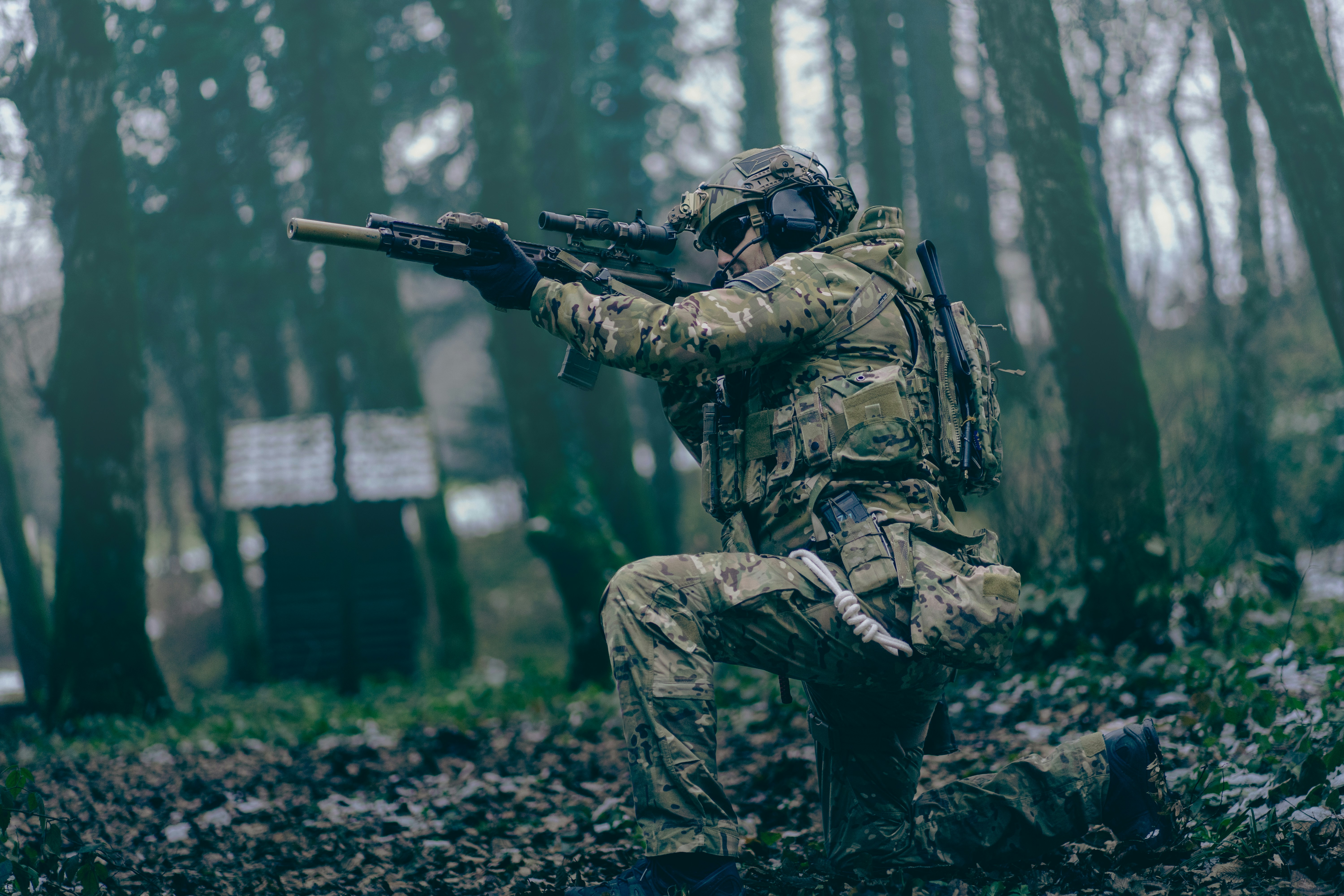 A man in camouflage holding a rifle in the woods