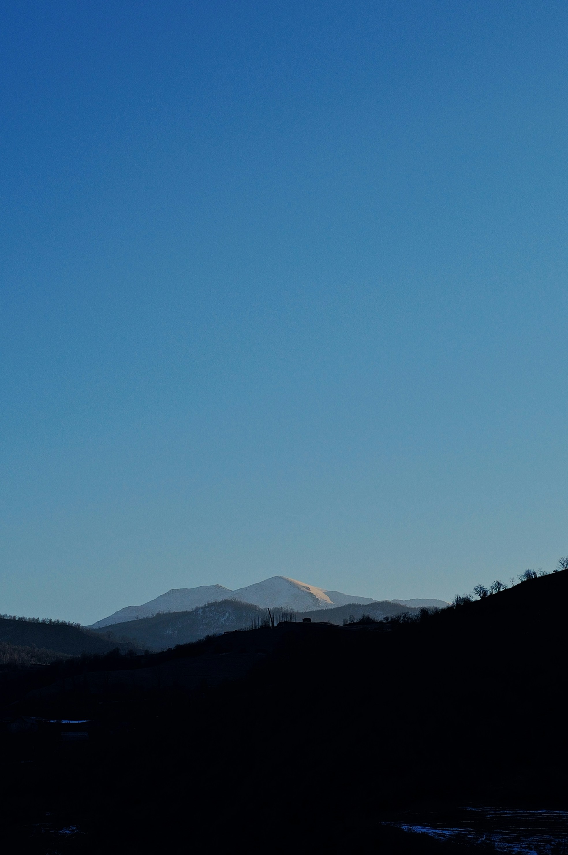 A view of a mountain range with a blue sky in the background