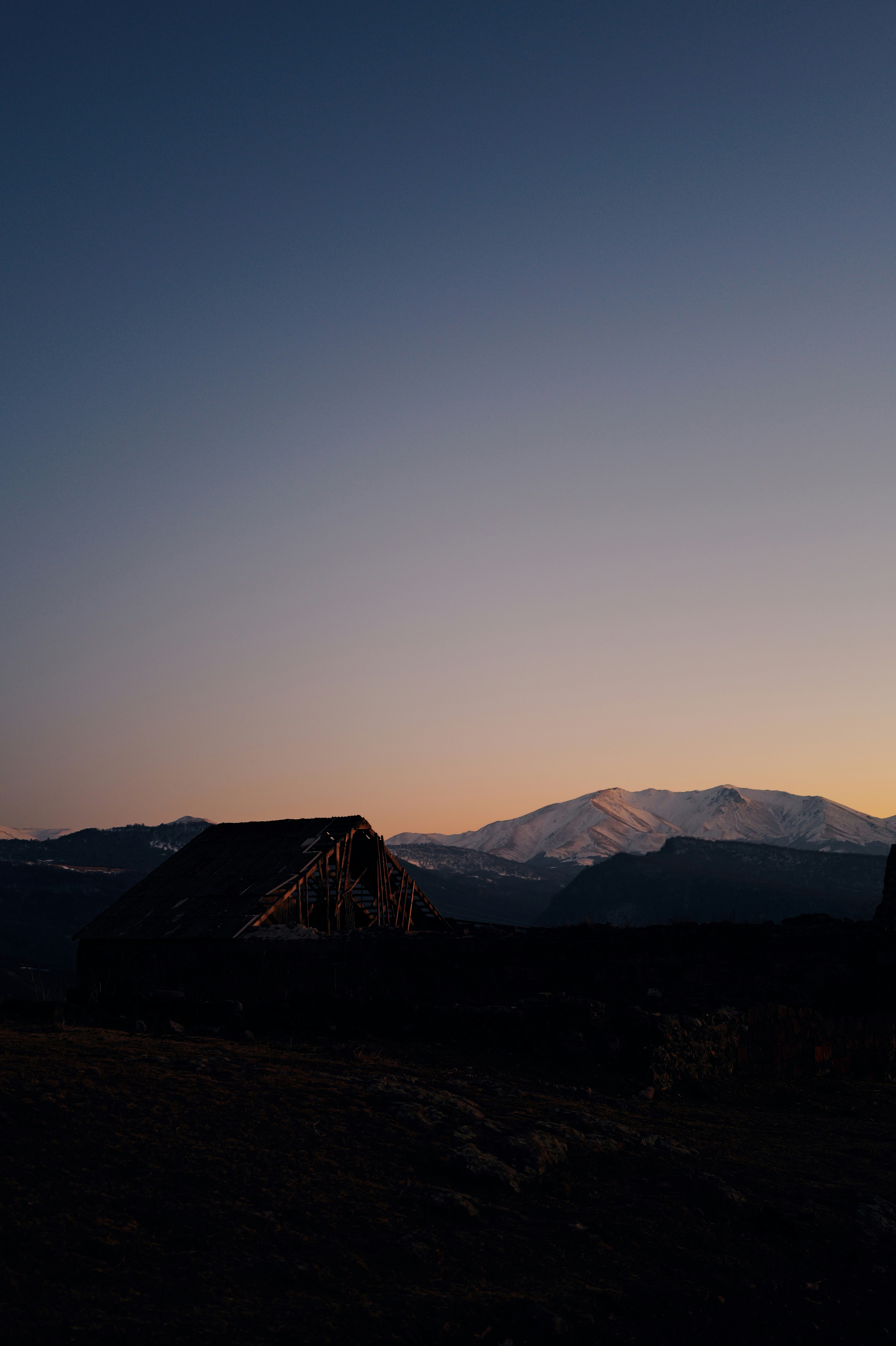 A silhouette of a house in the distance with mountains in the background